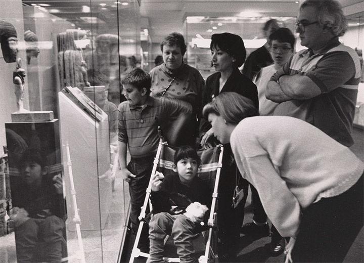 Archival photo of adults and children looking at Egyptian art.
