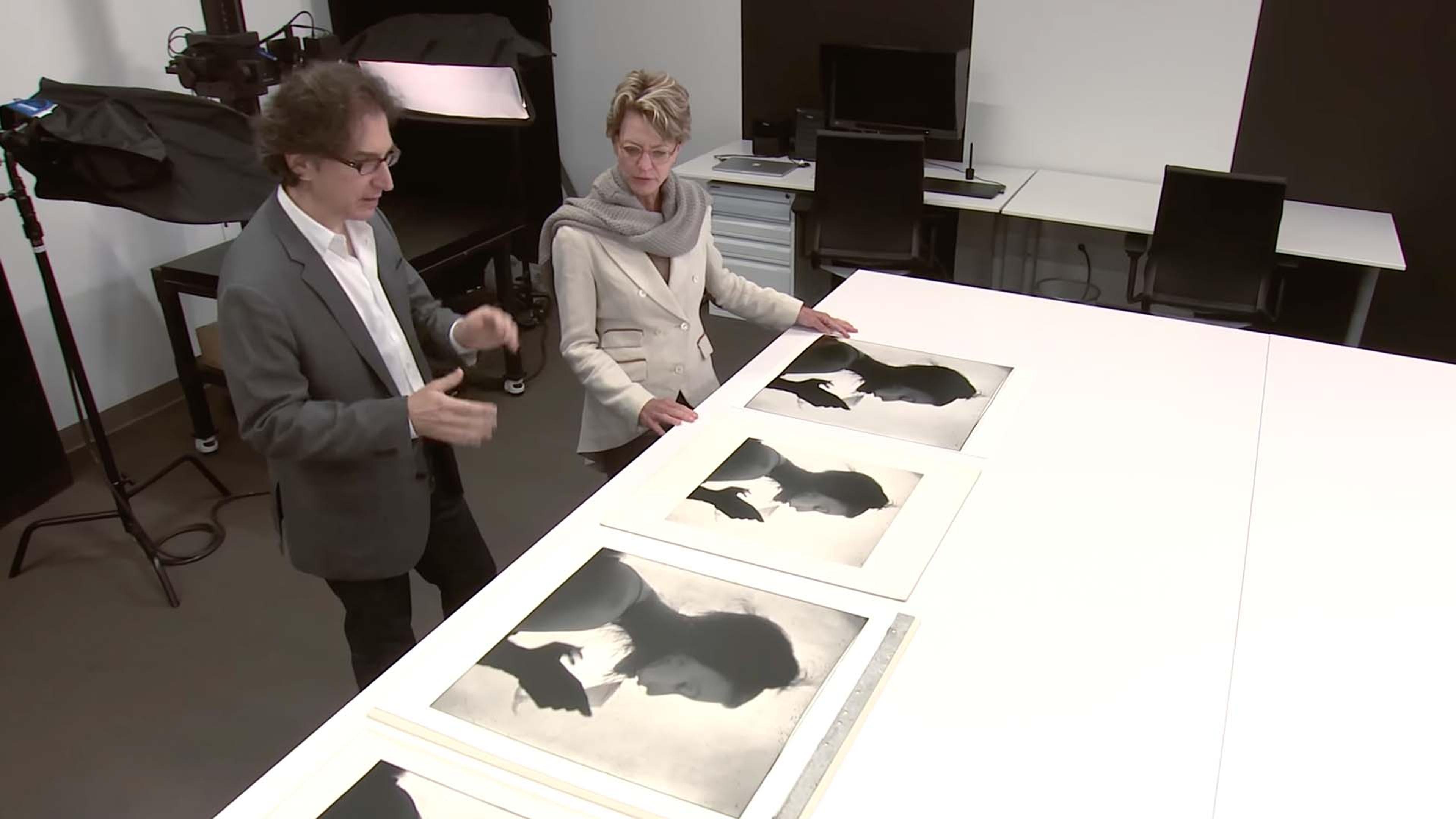 Two people looking at photographs on a table