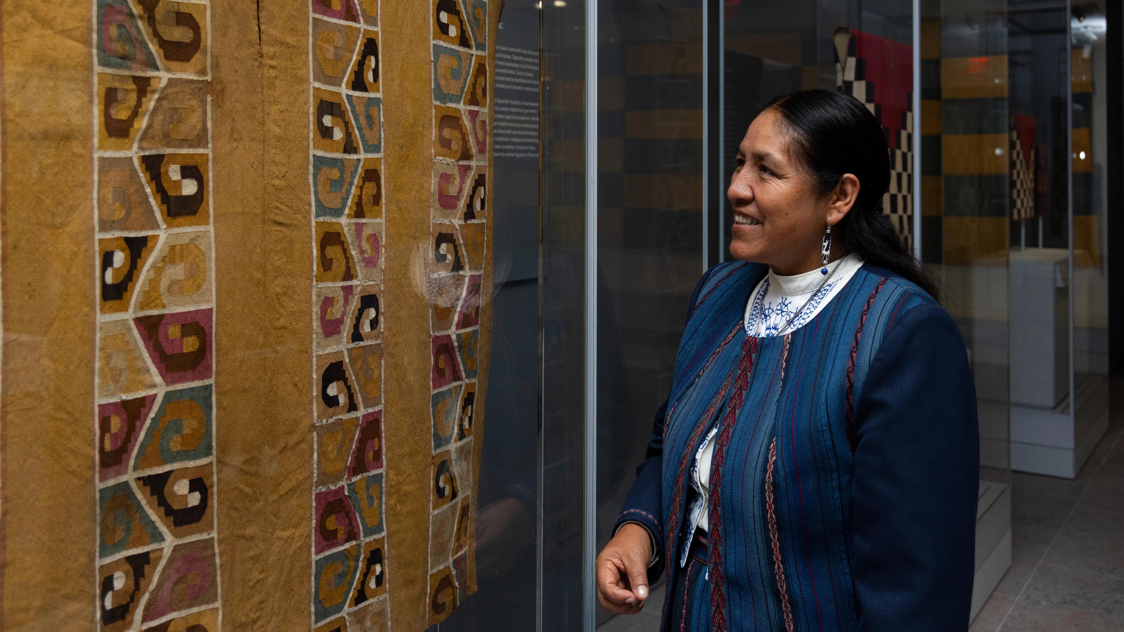 Nilda Callañaupa Alvarez looks at a weaving in the Arts of the Ancient Americas textile gallery