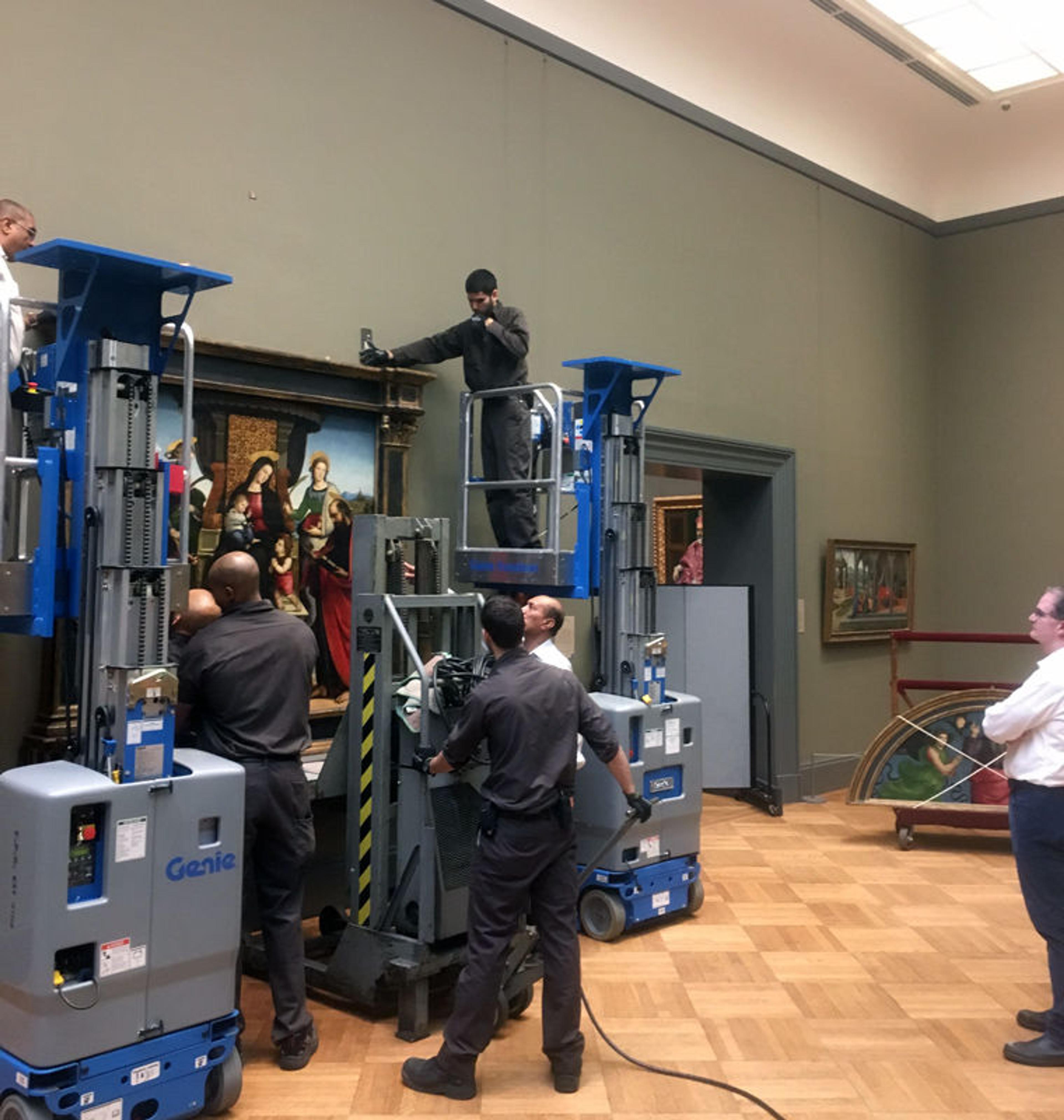 Museum staff move an altarpiece by Raphael in an art gallery