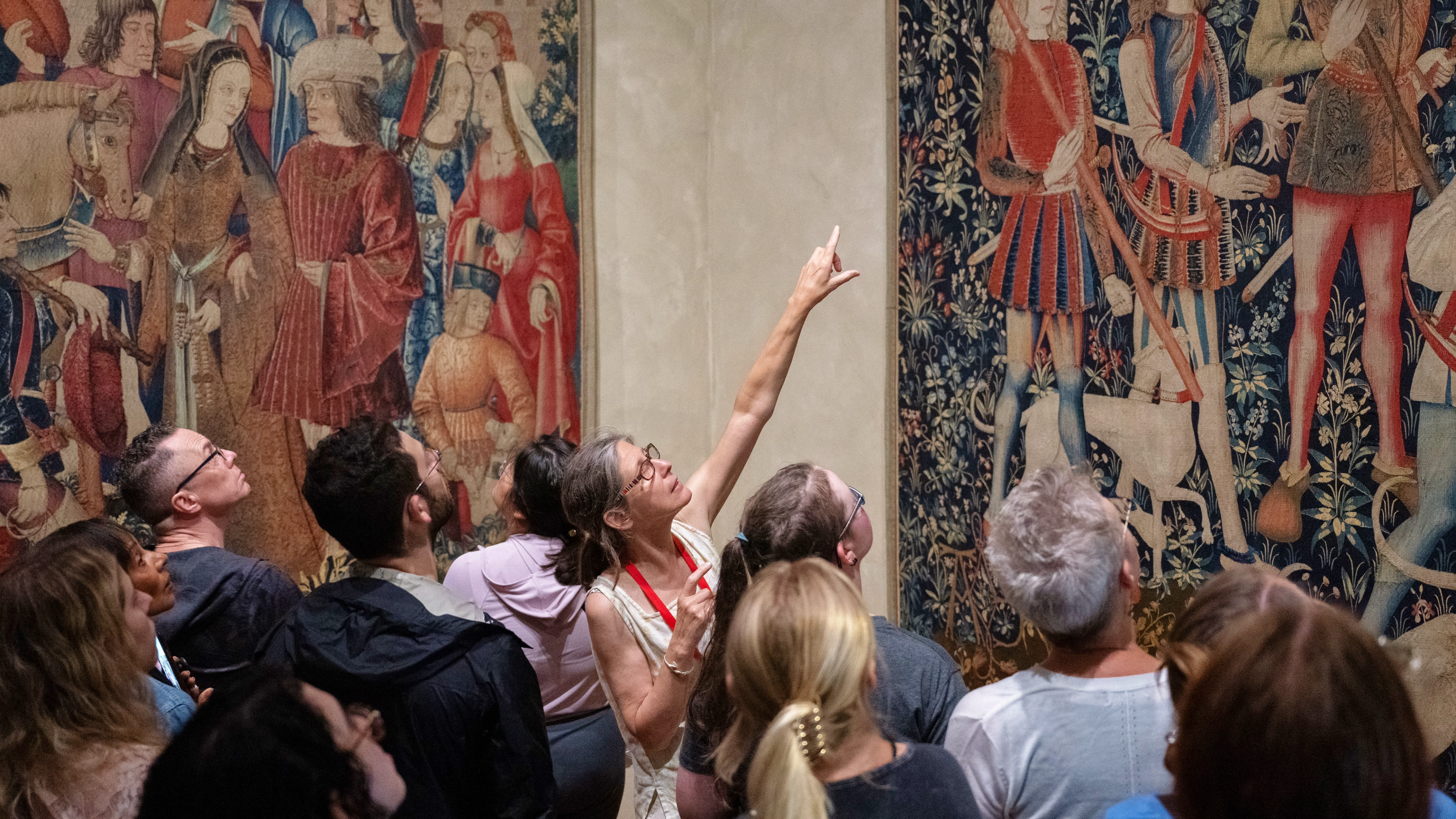 A tour guide points at an artwork with a group surrounding them. 