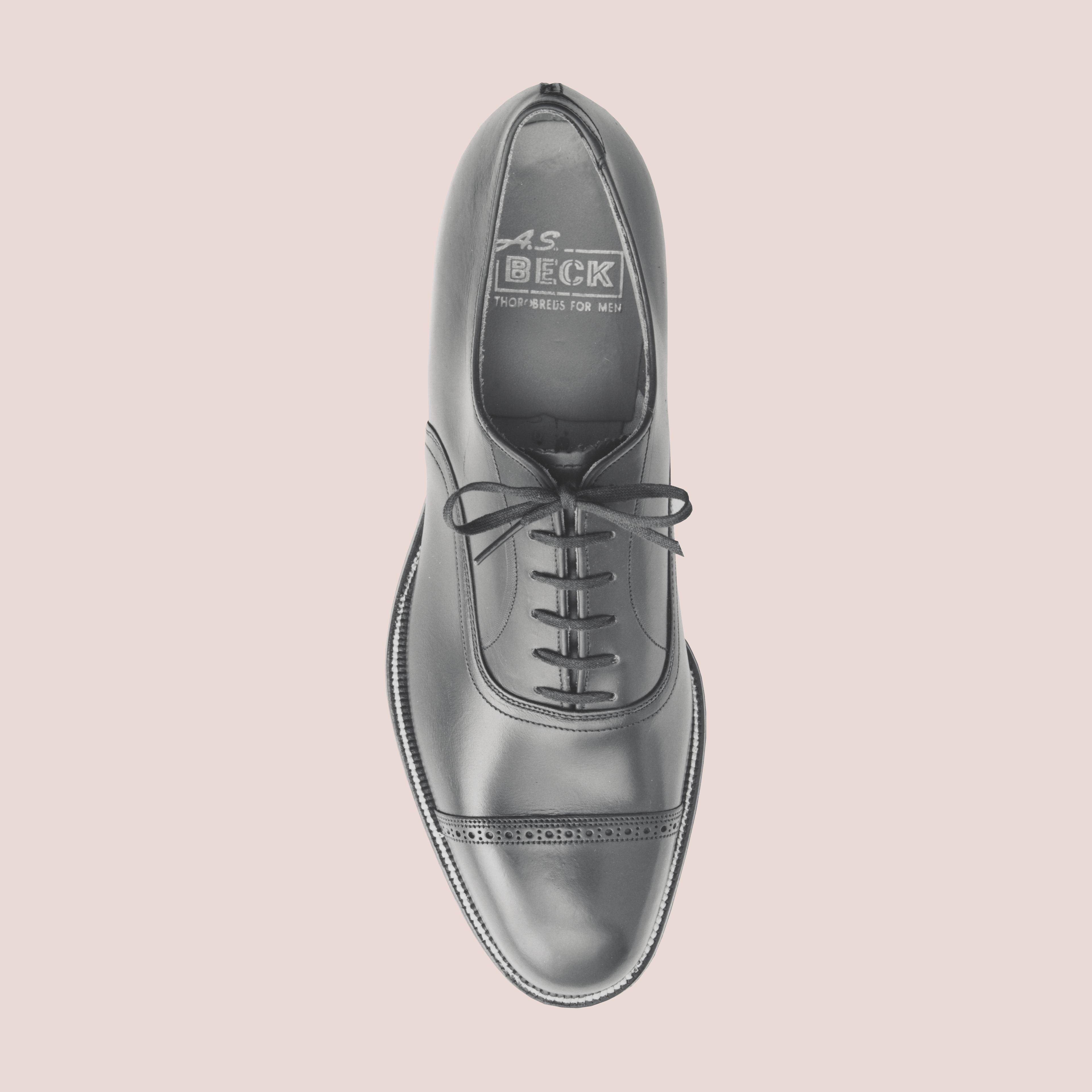 Blush background with a gentlemen's shoe in the center.