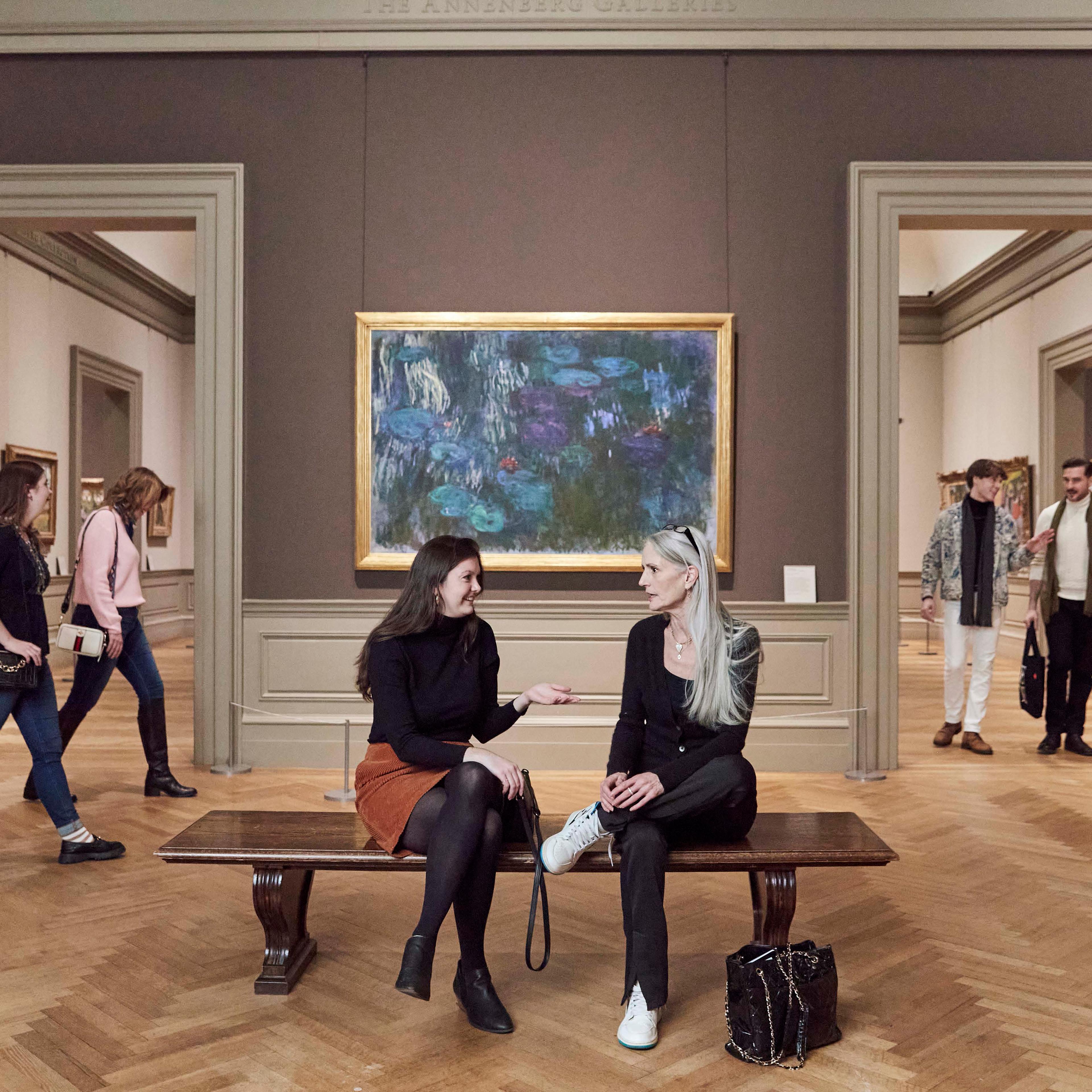 Three pairs of people walking and sitting in a 19th Century Gallery in The Met.