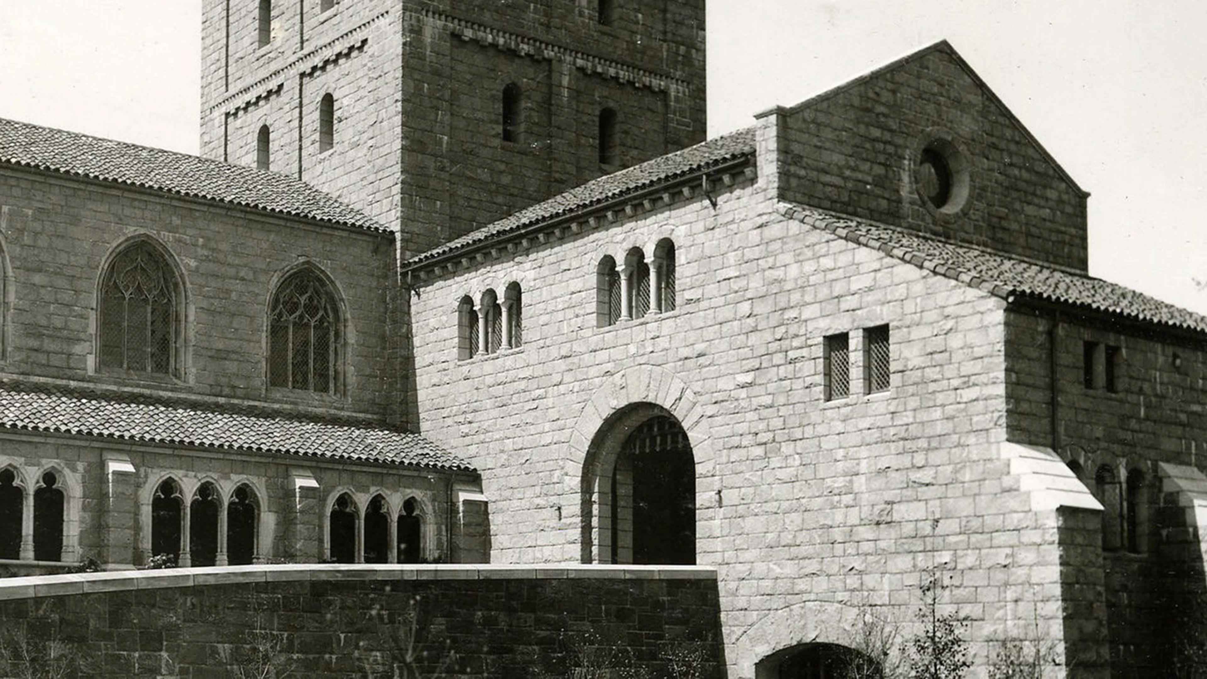    A stone Romanesque-style building with a tall square tower, rounded arches, and grouped windows, shown from the exterior of the Met Cloisters