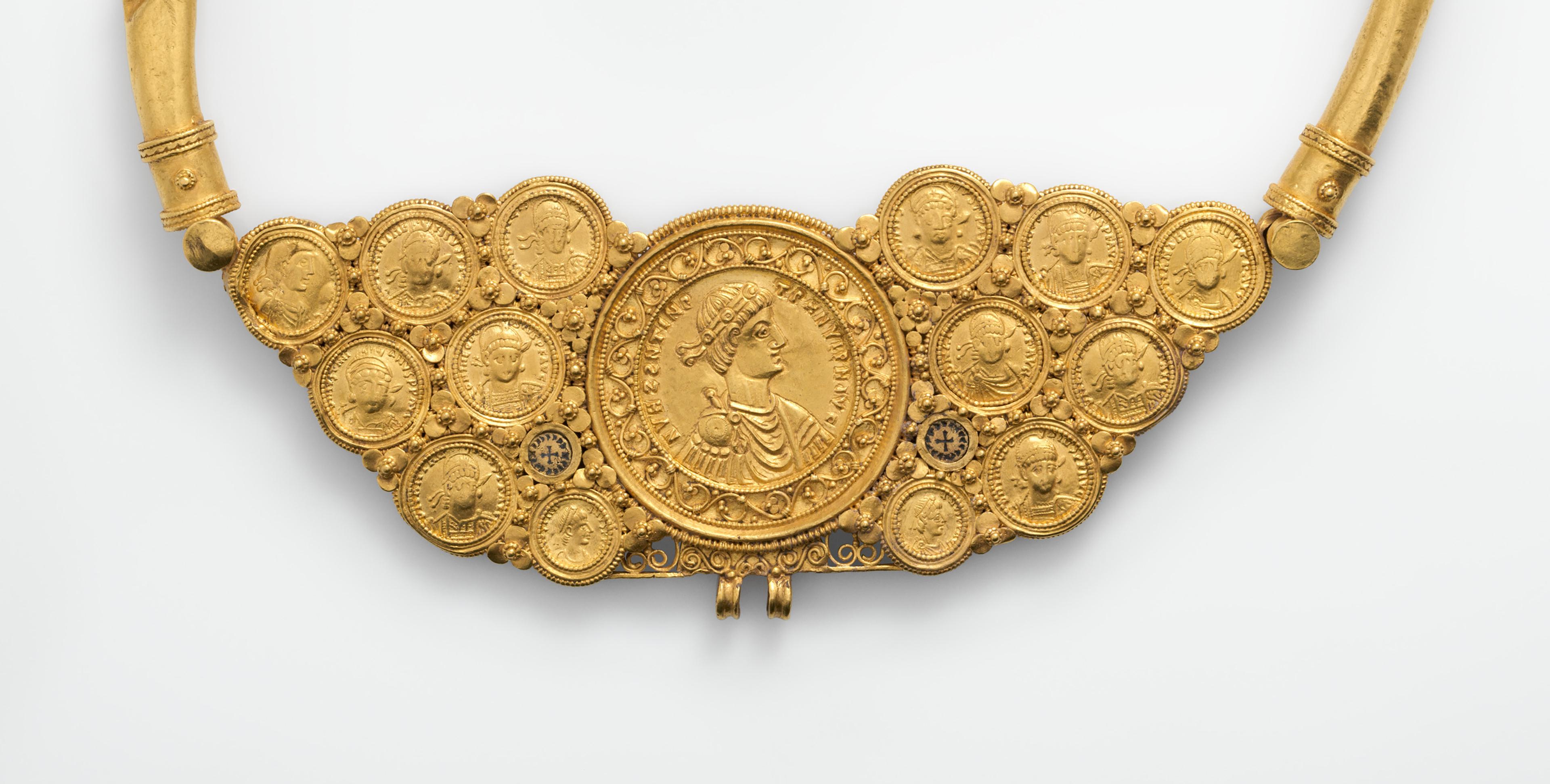 Image of a necklace with gold coins with peoples faces on it. 