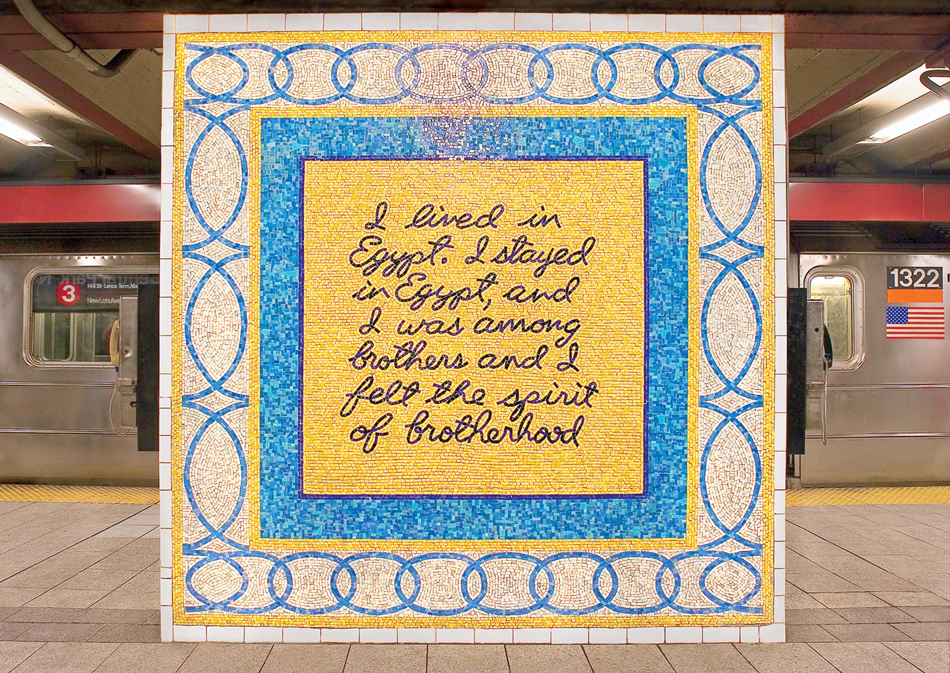 A yellow and blue mosaic in a metro station with writing in dark blue that says" I lived in Egypt. I stayed in Egypt and I was among brothers and I felt the spirit of brotherhood."