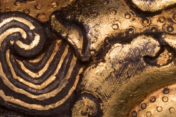 Microscopic view of wire damascening evident in crosshatching wear pattern (right) and individual wire-hair coils (left), as well as of textured scales imparted through circular punches visible on right