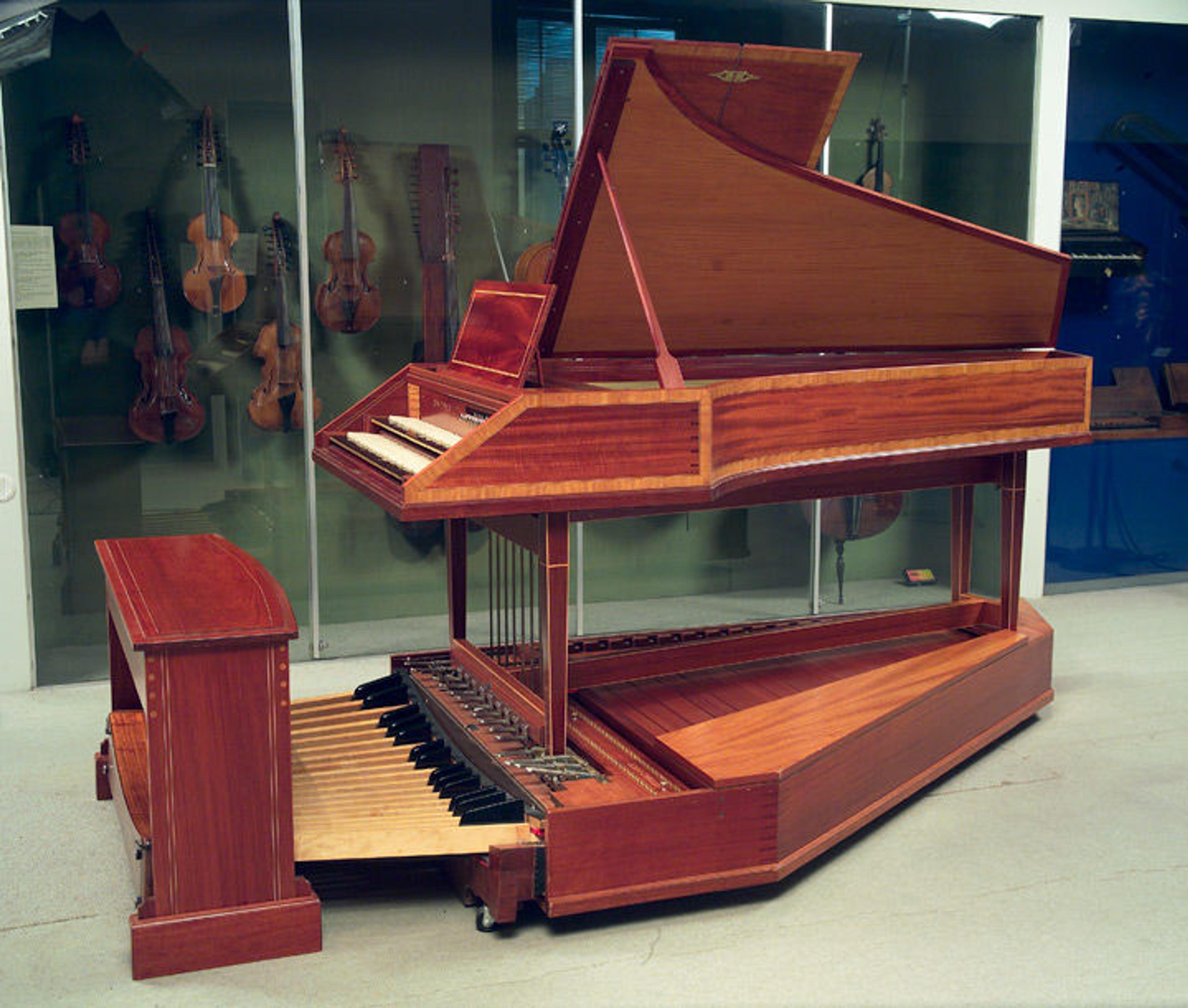 View of a pedal harpsichord in a gallery surrounded by an assortment of stringed instruments