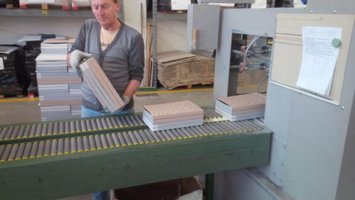 Man pulling a stack of books off a conveyor belt