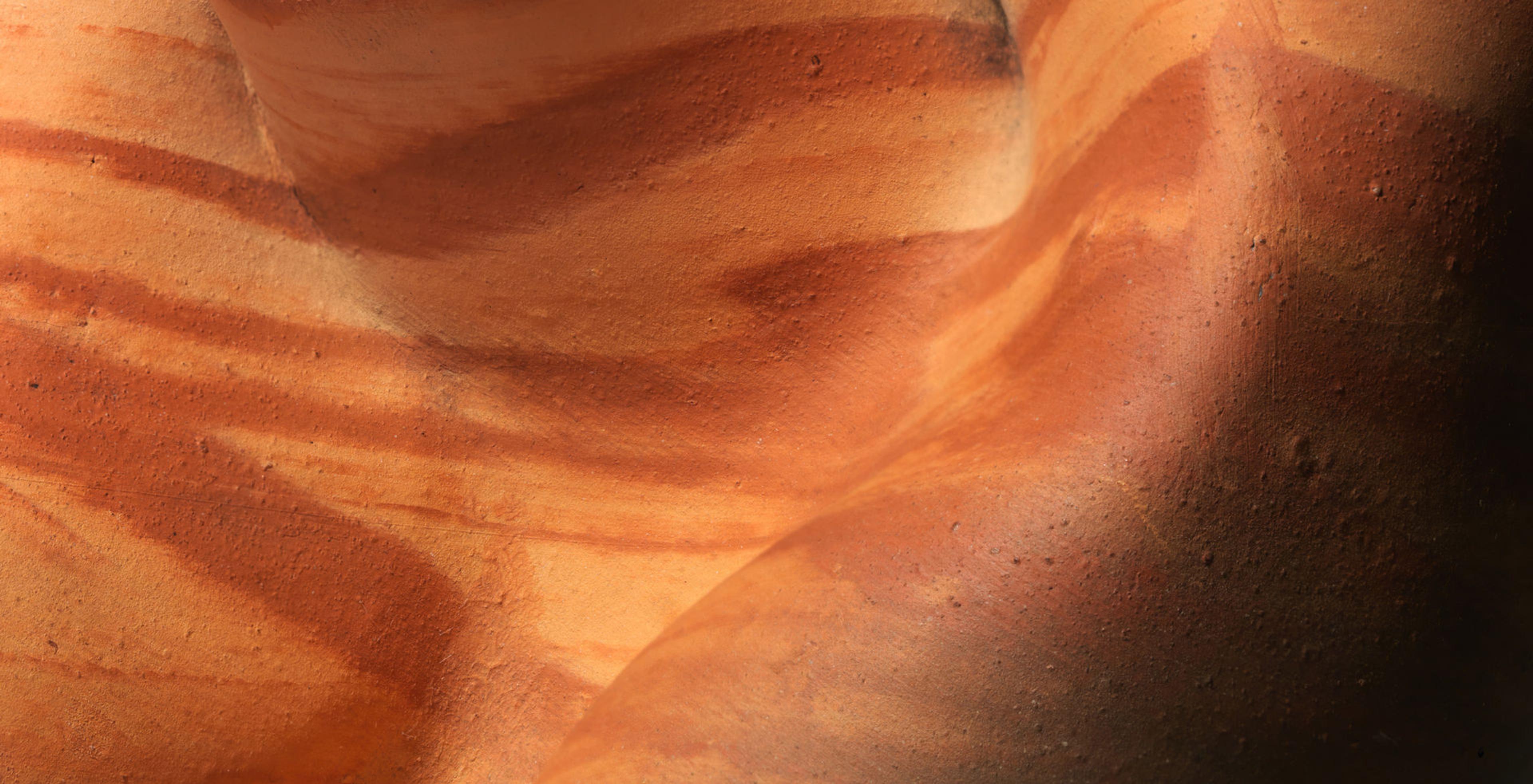 Detail of the curves of a clay vessel with stripes of dark and light red clay