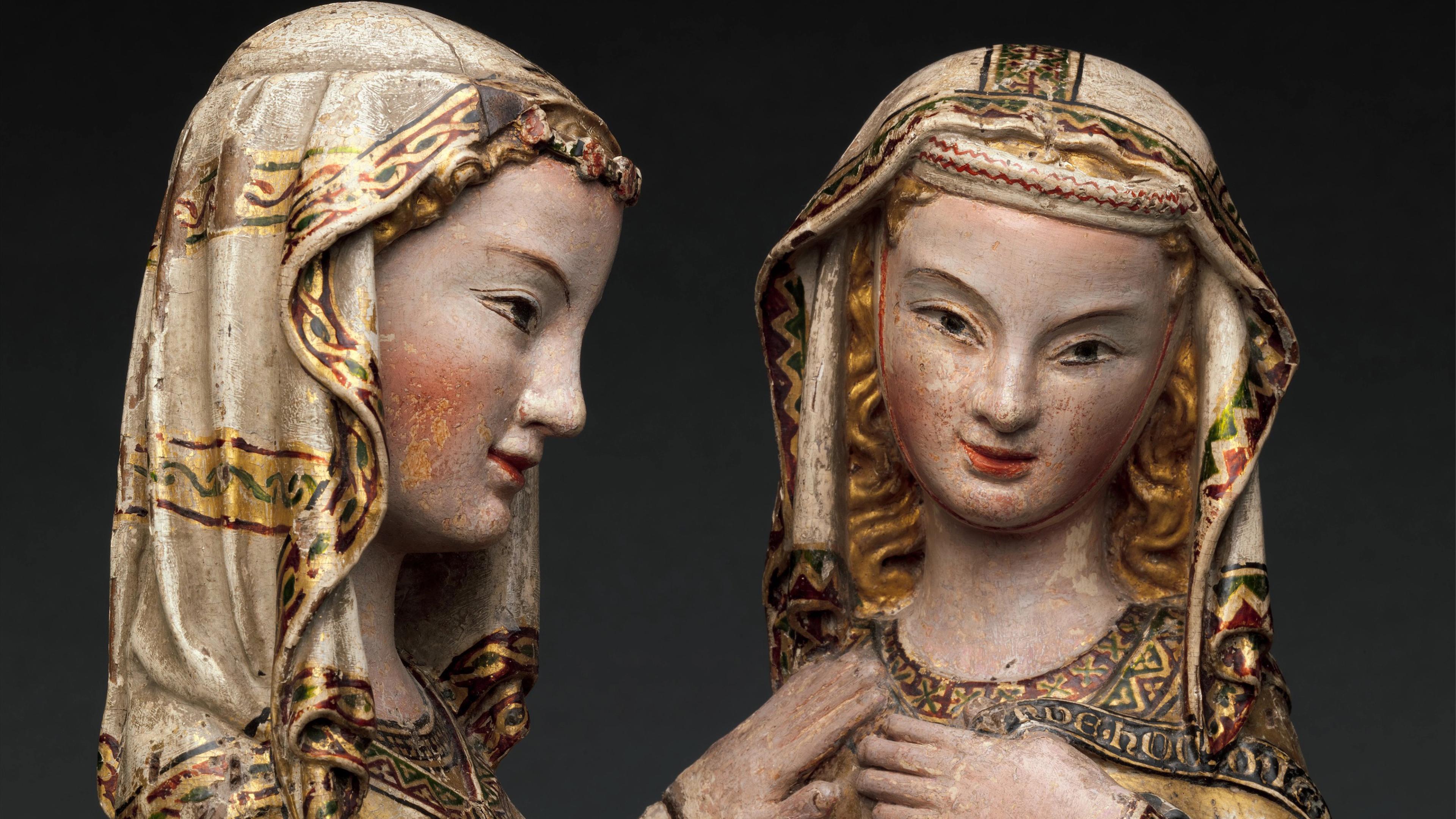 Two medieval sculptures of women with serene expressions, wearing ornate headdresses and robes with intricate patterns, set against a dark background.