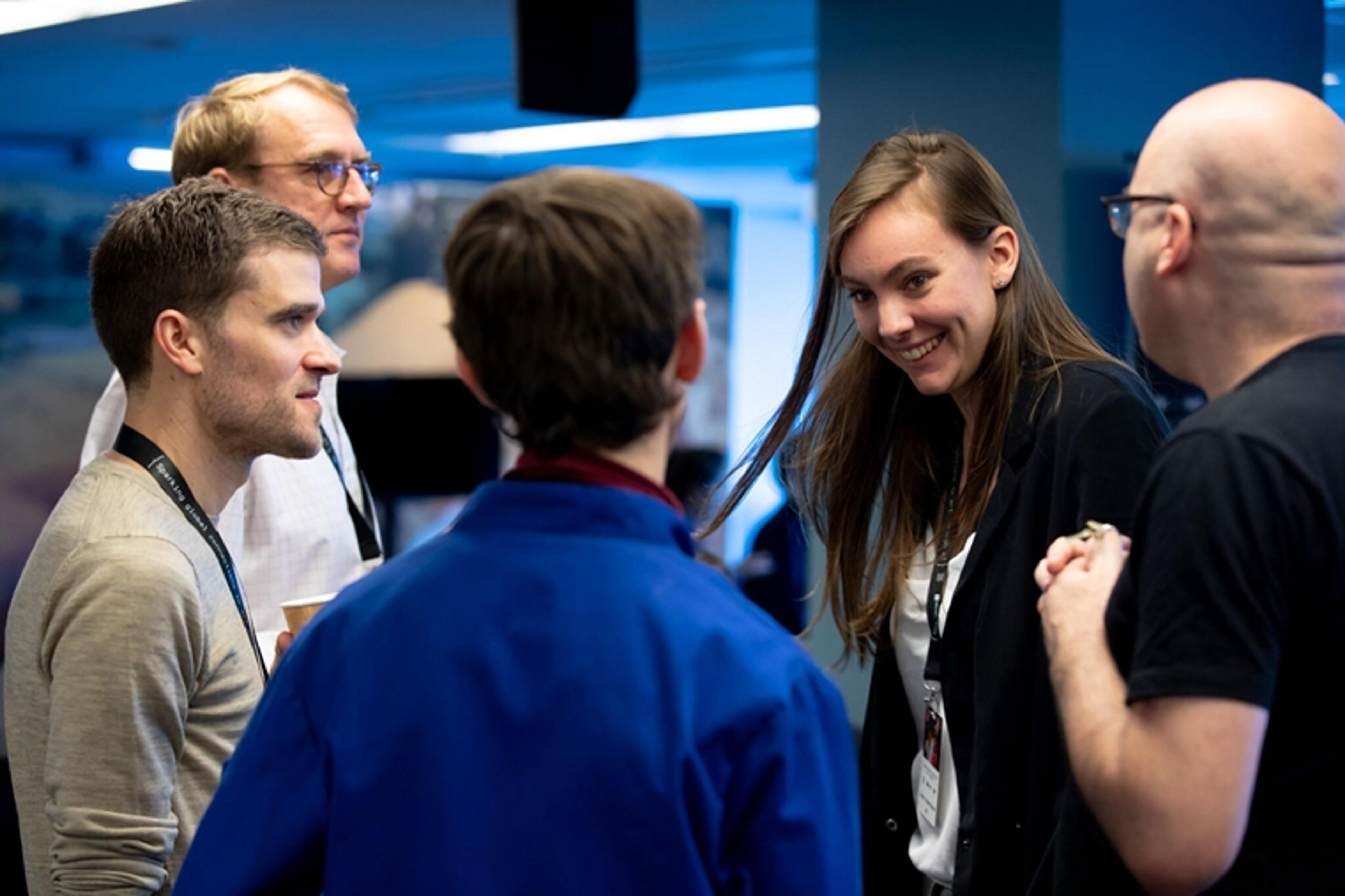 A group of people discuss AI at a hackathon event