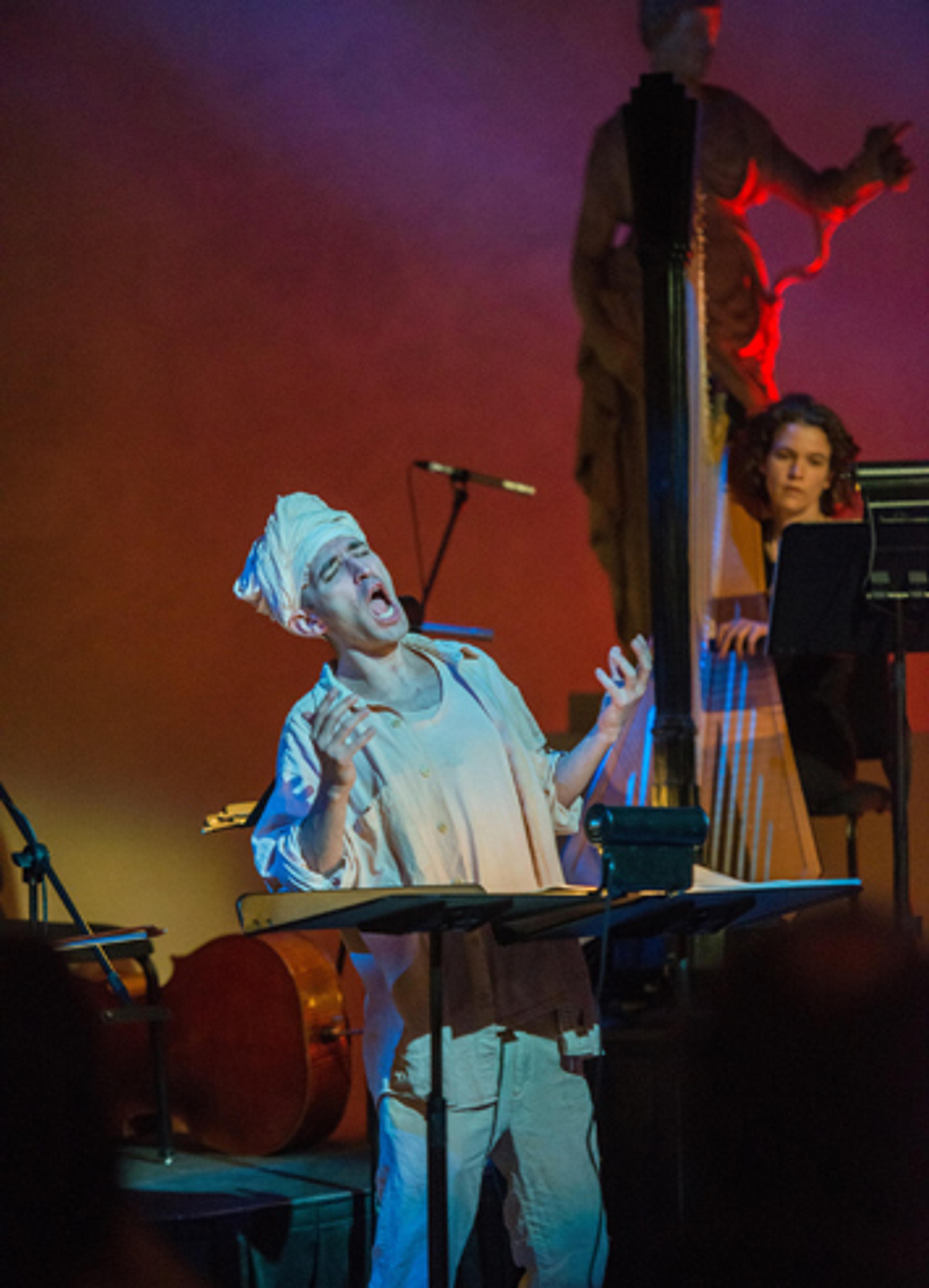Close-up of a singer expressing great emotion while accompanied in the back by a harp player