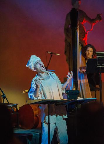 Close-up of a singer expressing great emotion while accompanied in the back by a harp player