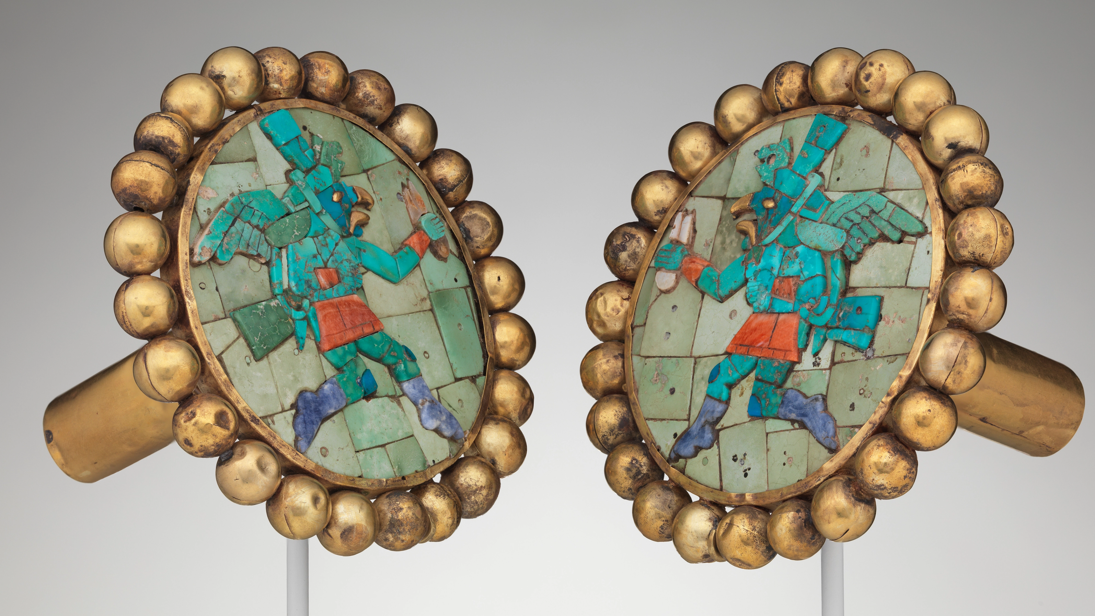 Moche artist(s) Ear ornament s with winged runner 400 – 700 CE Gold, turquoise, sodalite, shell H. 3 3/4 × W. 3 7/8 × D. 3 1/4 in. (9.5 × 9.8 × 8.3 cm) The Metropolitan Museum of Art, New York, Gift and Bequest of Alice K. Bache, 1966, 1977