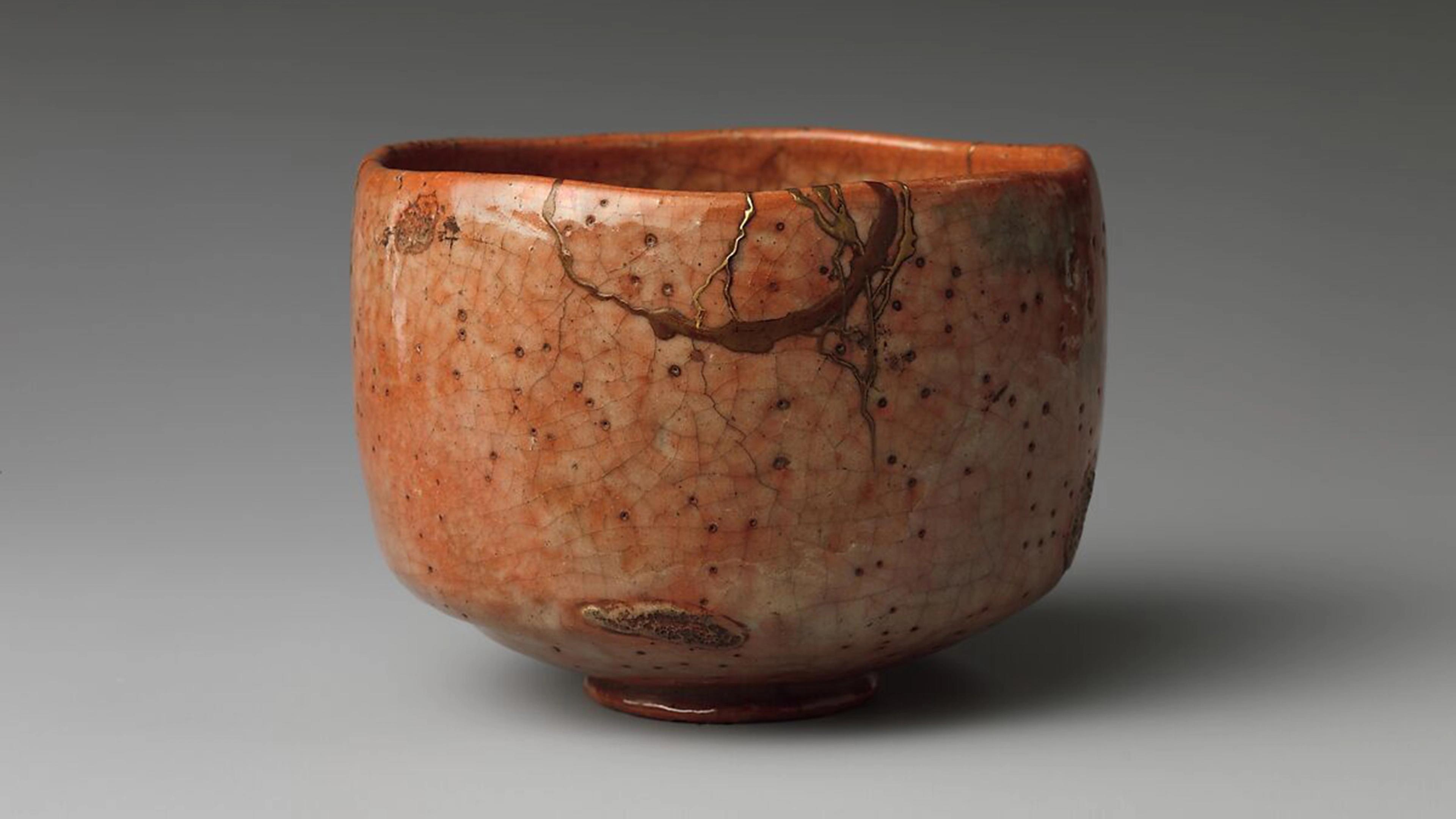 A reddish-brown tea bowl with speckling, dark veins, and cracked glazing throughout.
