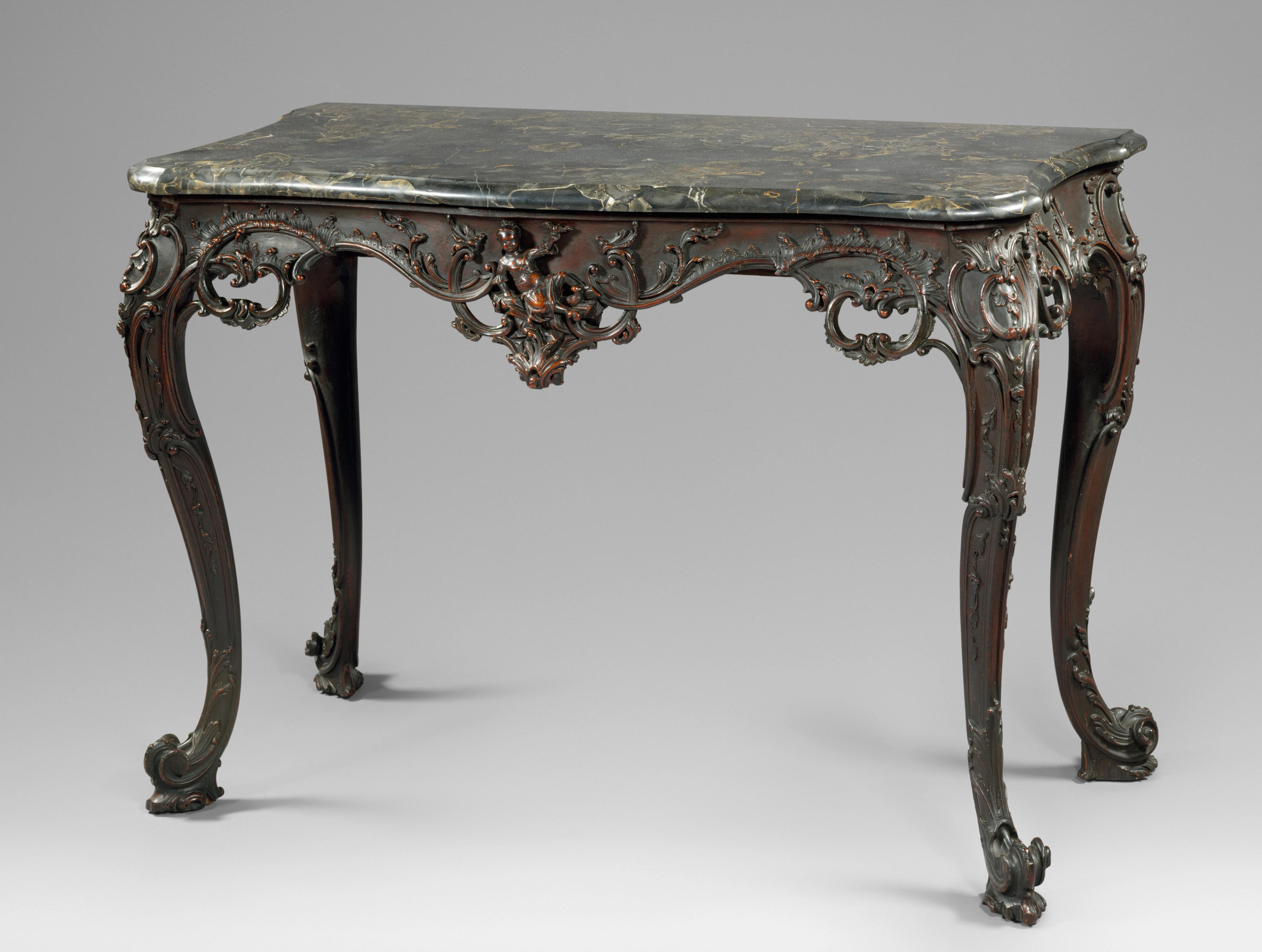 Slab table with black and green marble top, and dark, ornate wooden base