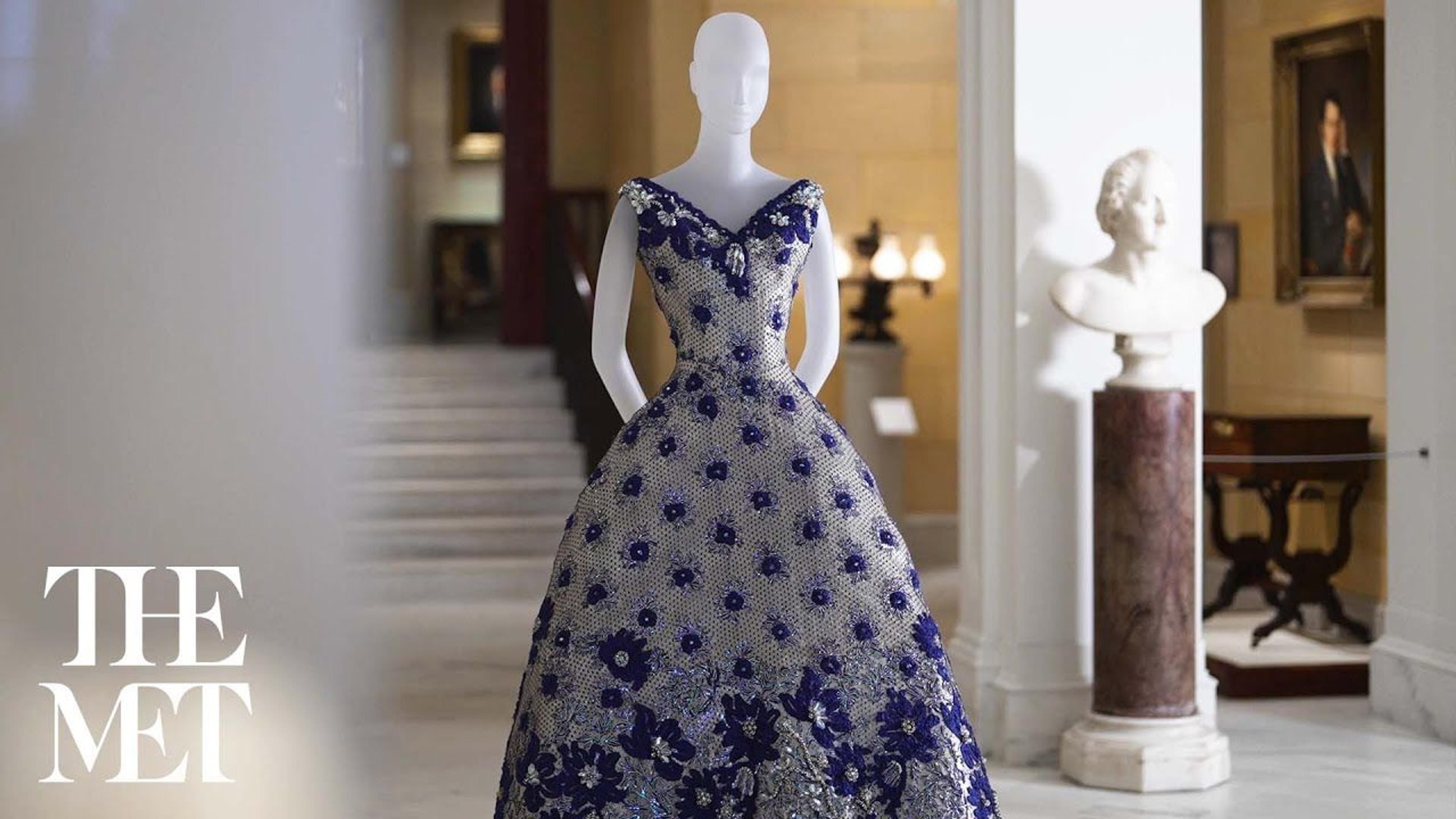 Mannequin in an evening gown stands in a stately interior space
