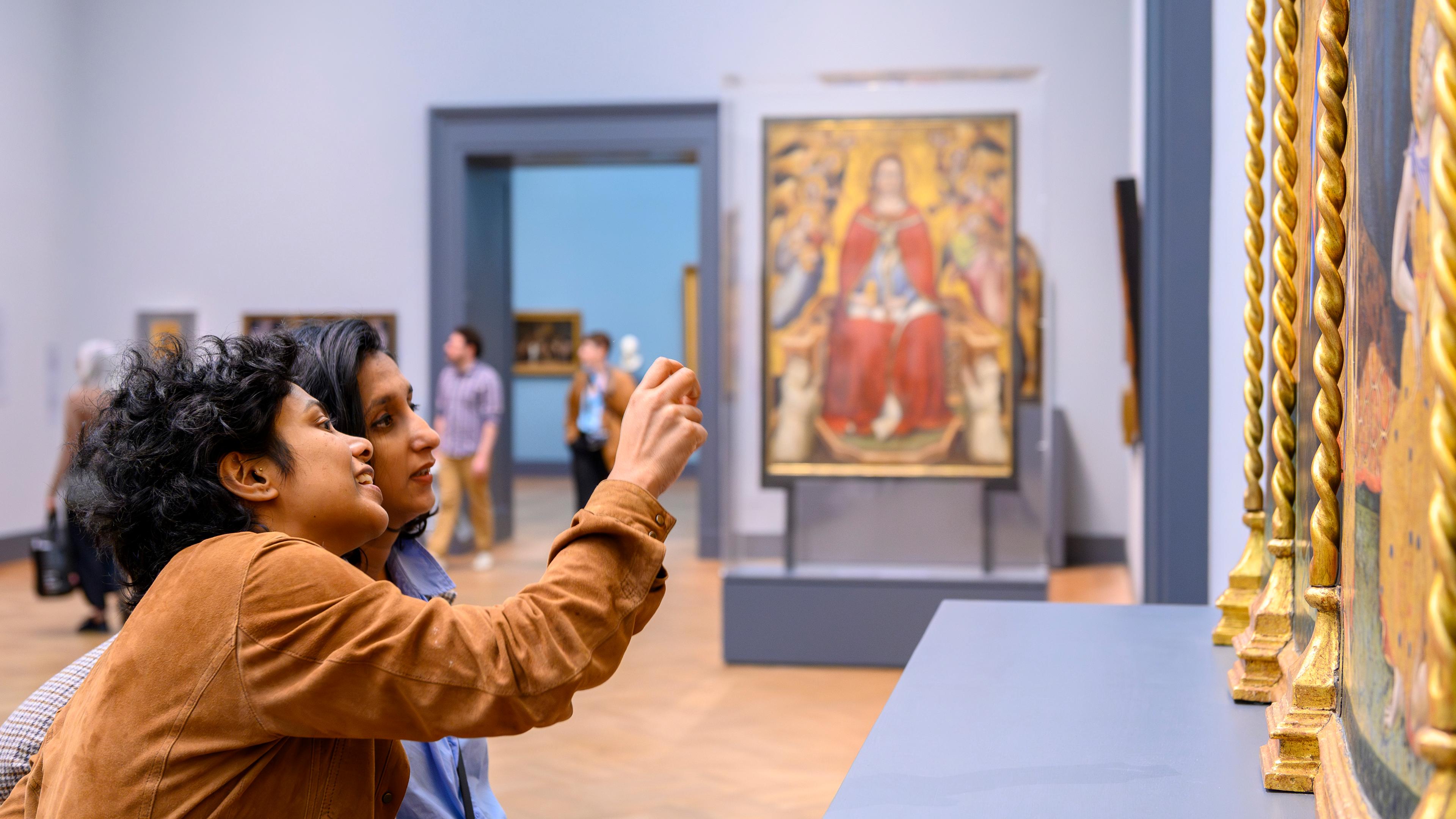 Two Museum visitors take a photo of a work of art in The Met's European Paintings galleries.