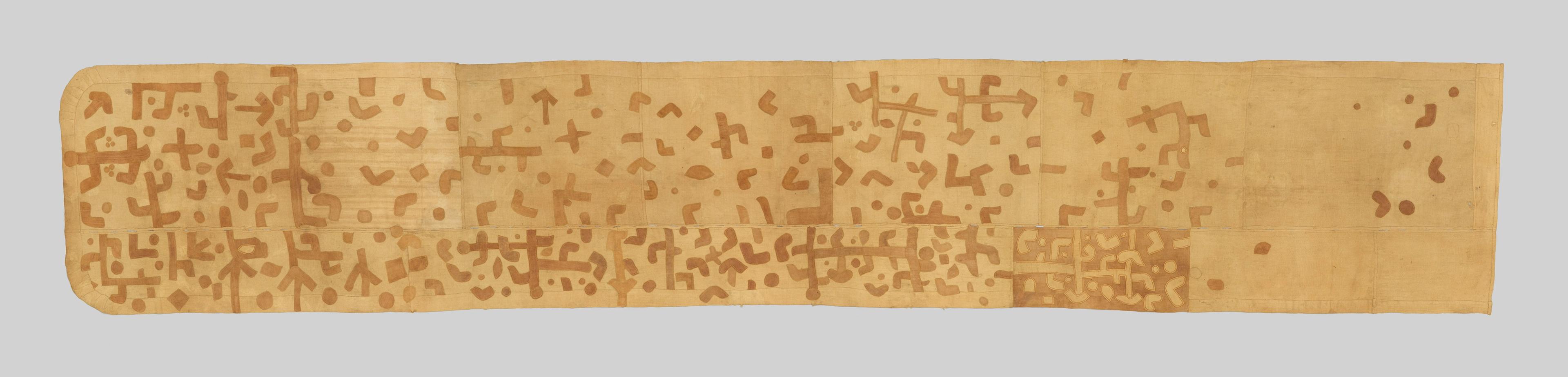 Beige wrap skirt covered with brown geometric symbols that fade and grow sparser across the length of the fabric.