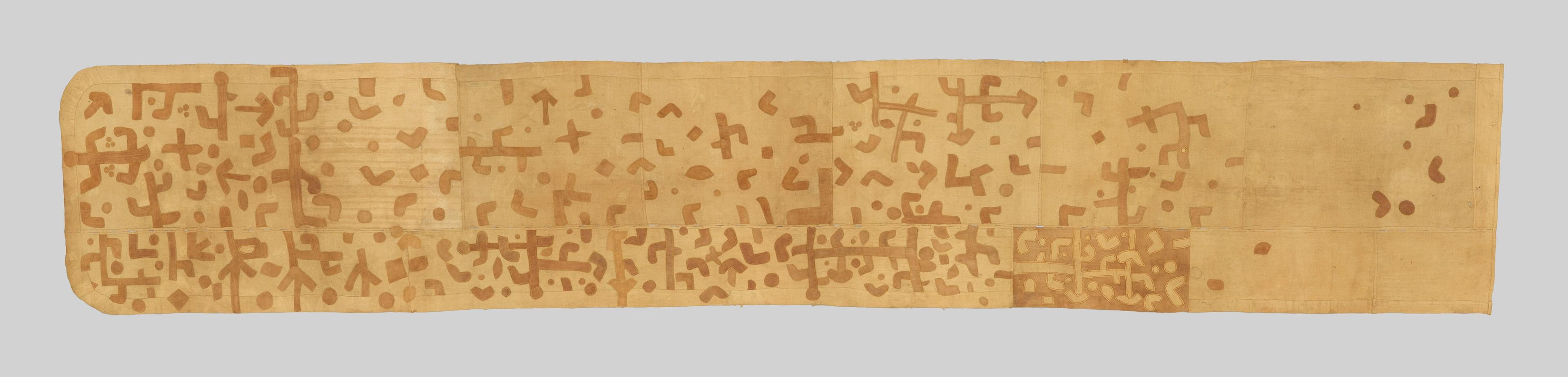 Beige wrap skirt covered with brown geometric symbols that fade and grow sparser across the length of the fabric.