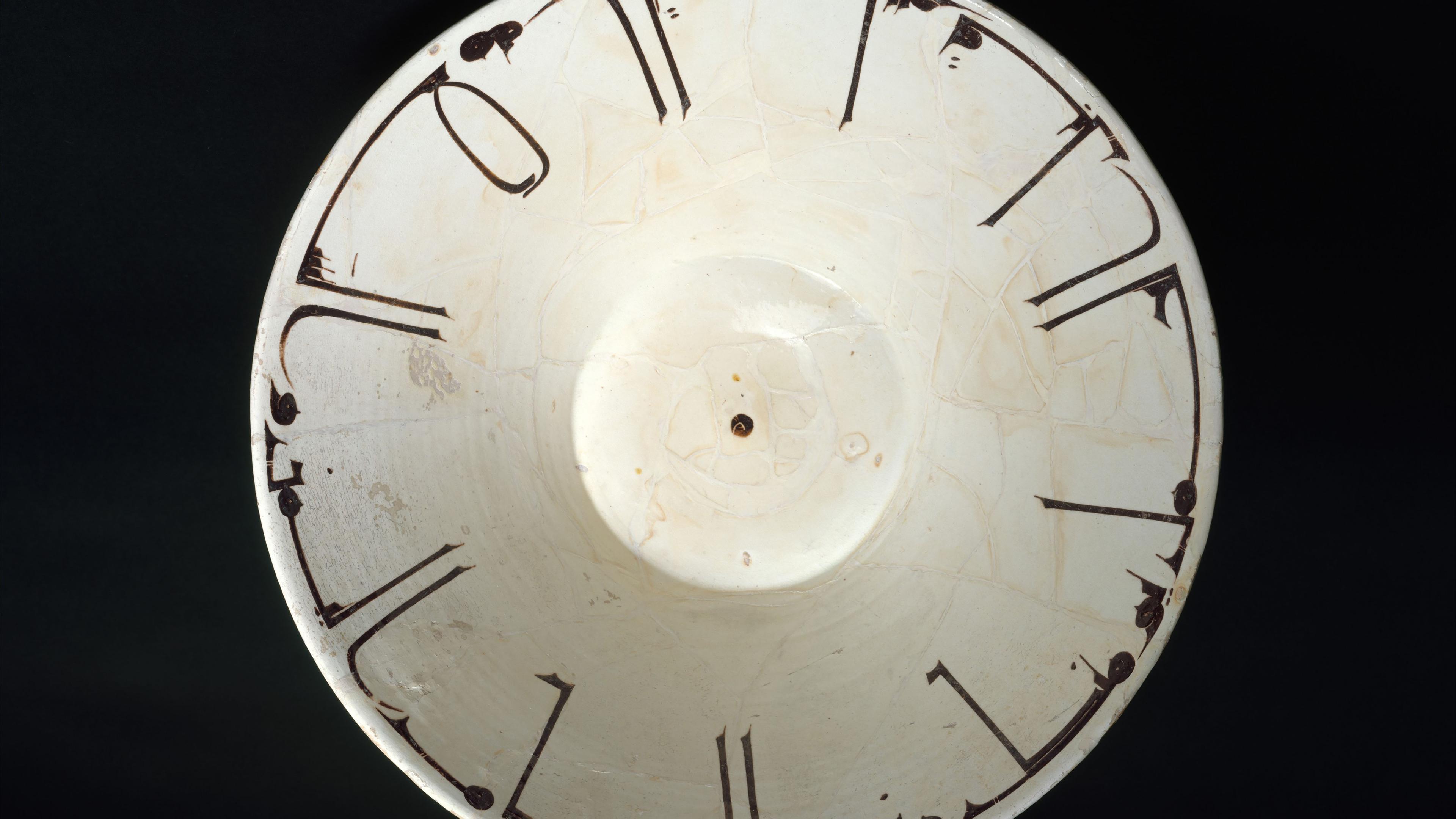 Off-white ceramic bowl with Arabic inscription in front of a black background