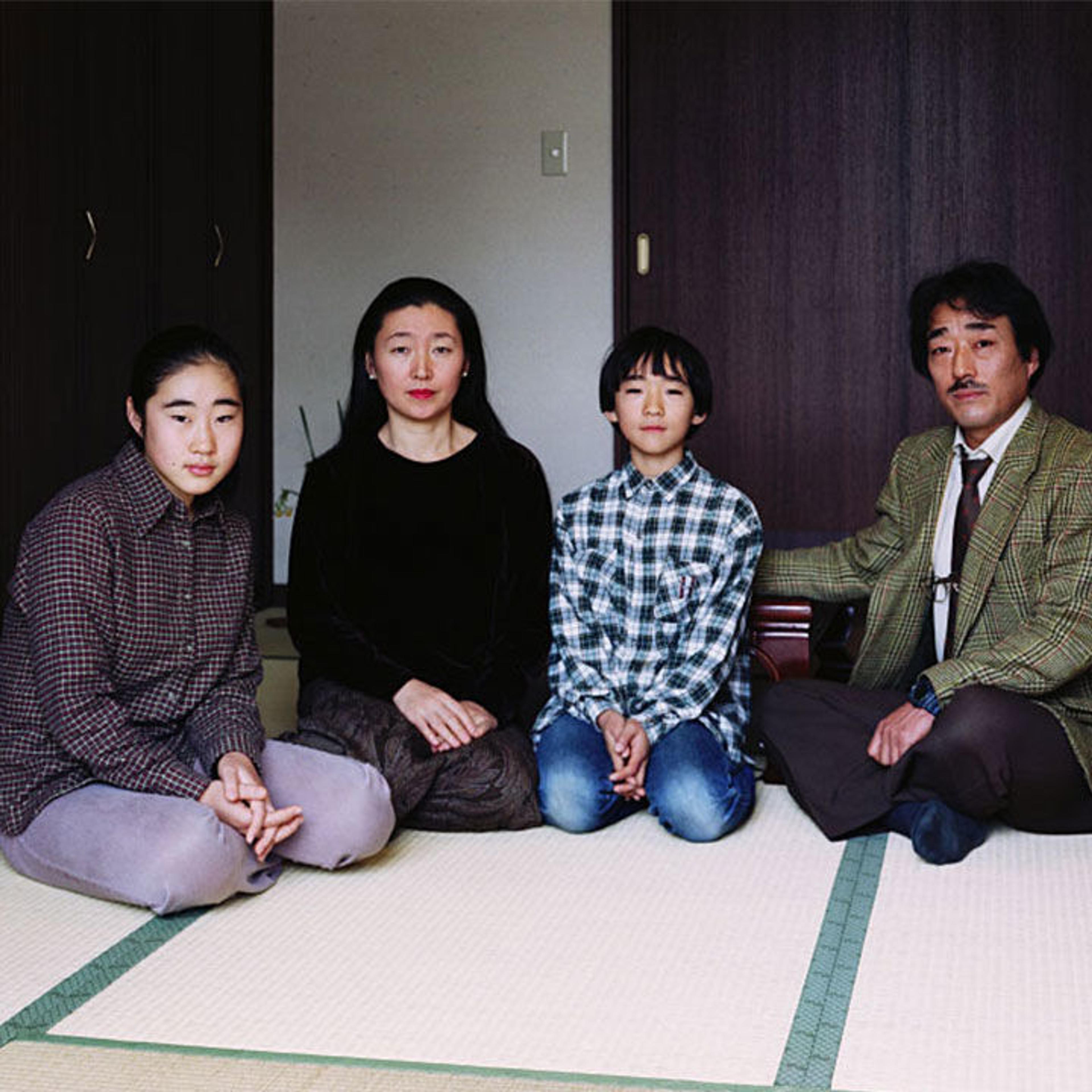 A family of four sits on tatami mats in a room with wooden doors