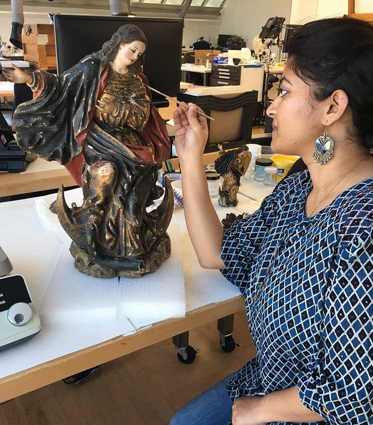 P. M. Vasundara preparing to consolidate flaking paint on Virgin of Quito, an eighteen-century polychrome wood sculpture from Ecuador