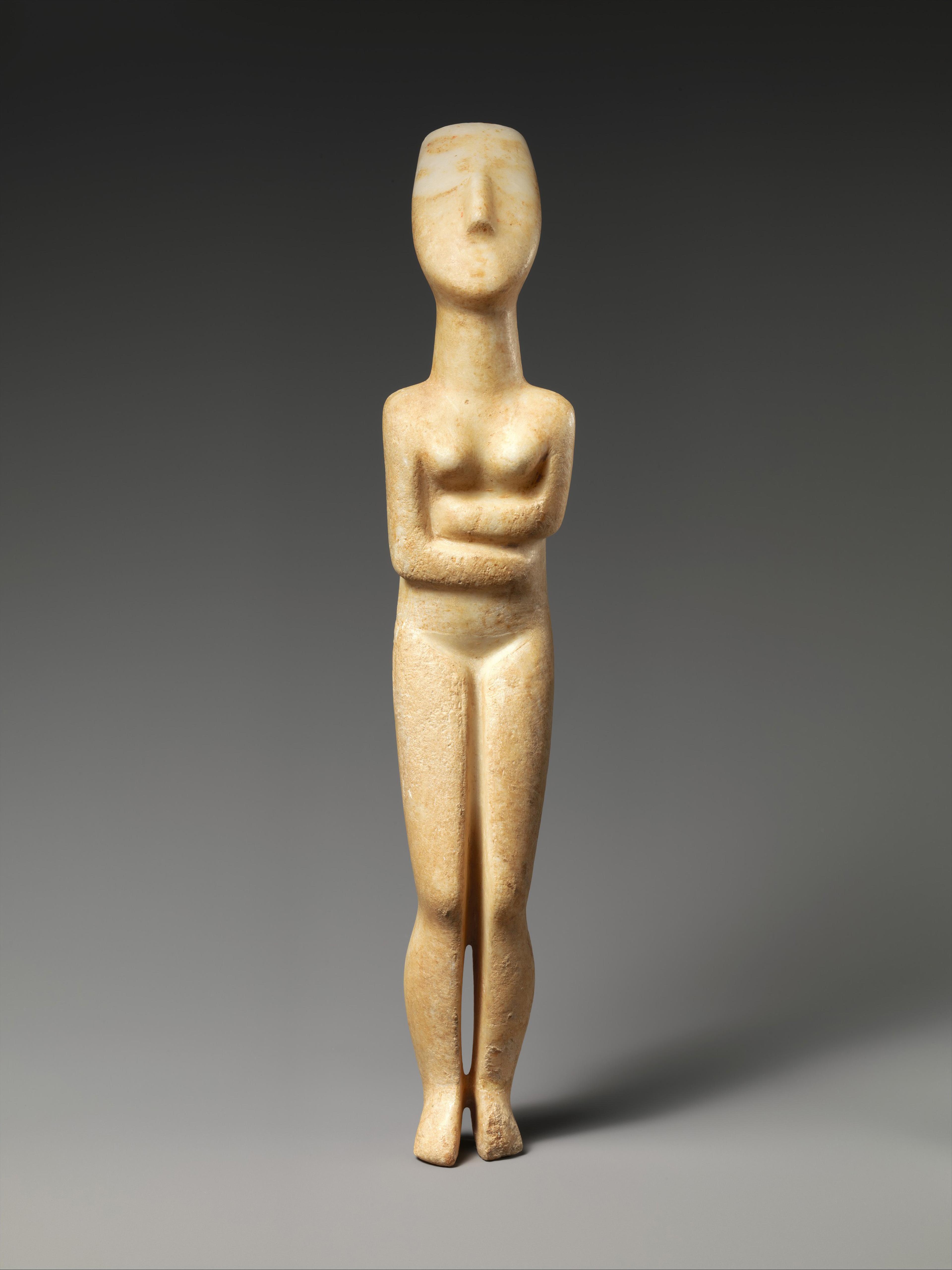 Marble figurine of a standing woman with folded arms and simplified features against a gray background.