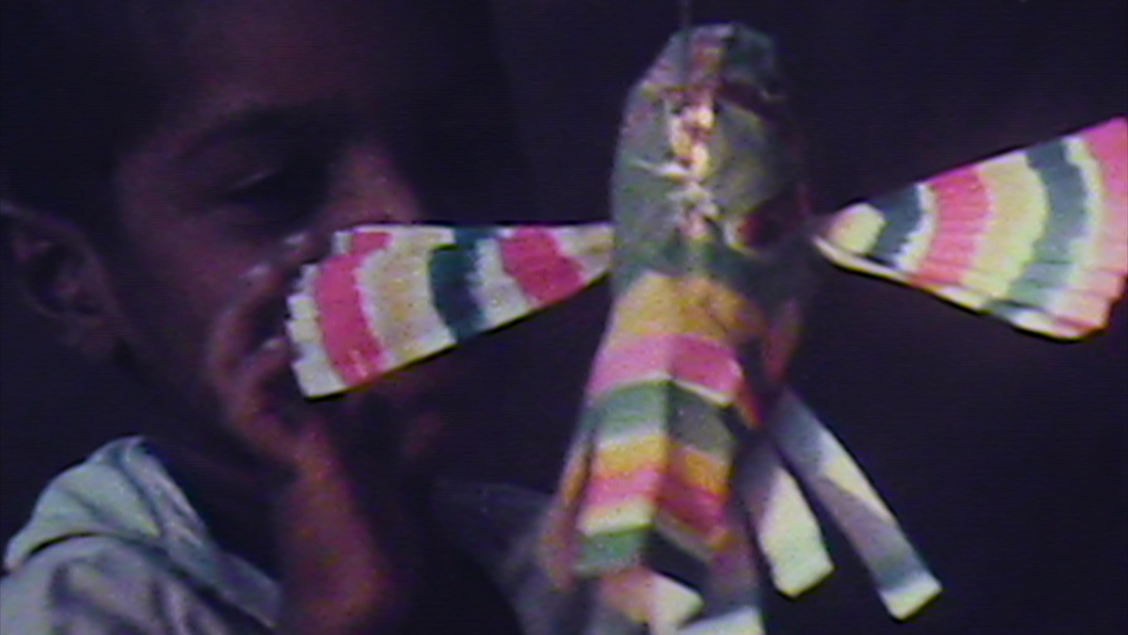 A child holds up a multicolored paper ornament in a fuzzy image