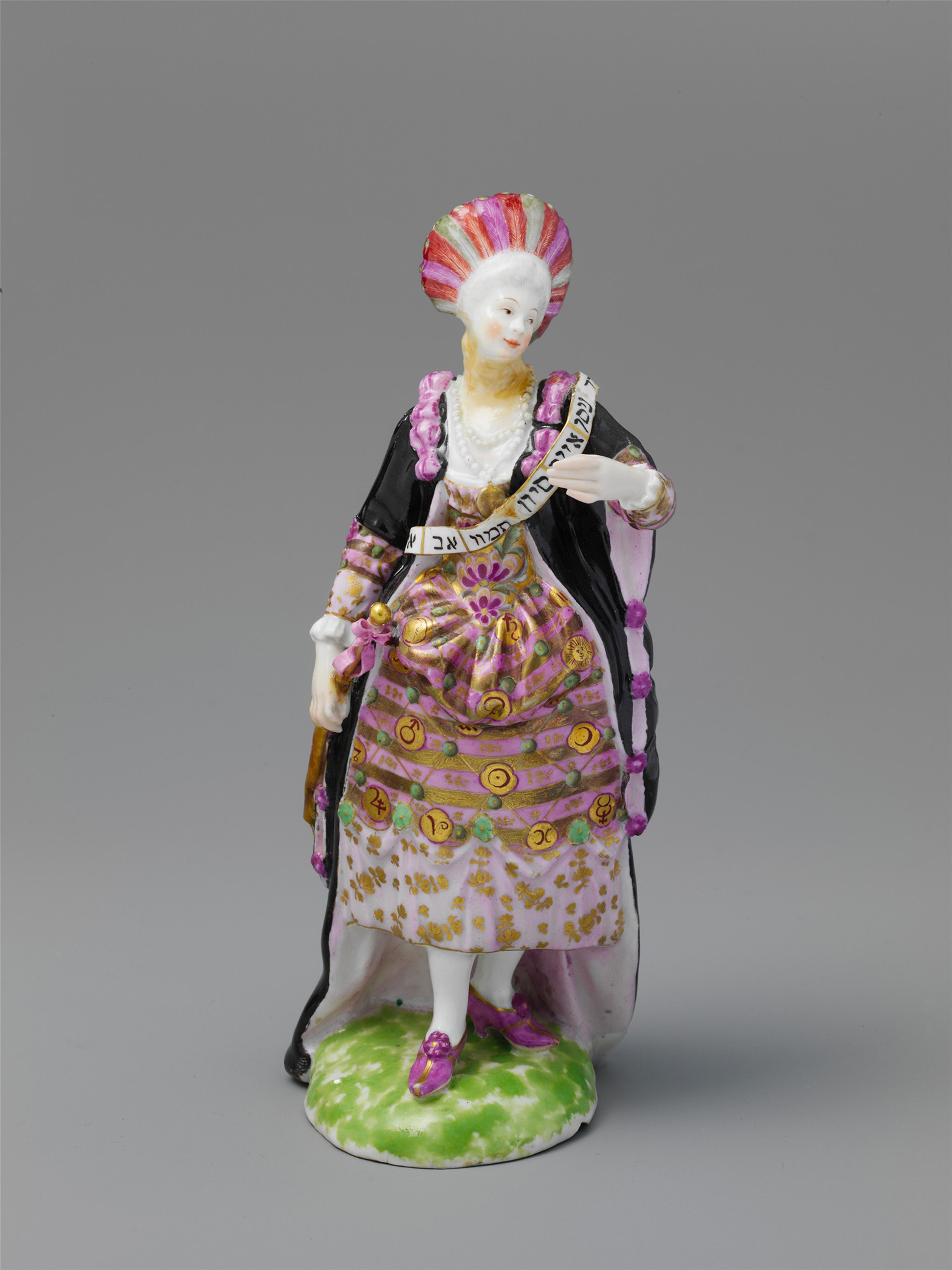 porcelain figurine of a woman in ornate 18th-century dress with pink and gold patterns, black cloak, and a fan. She stands on a green base.