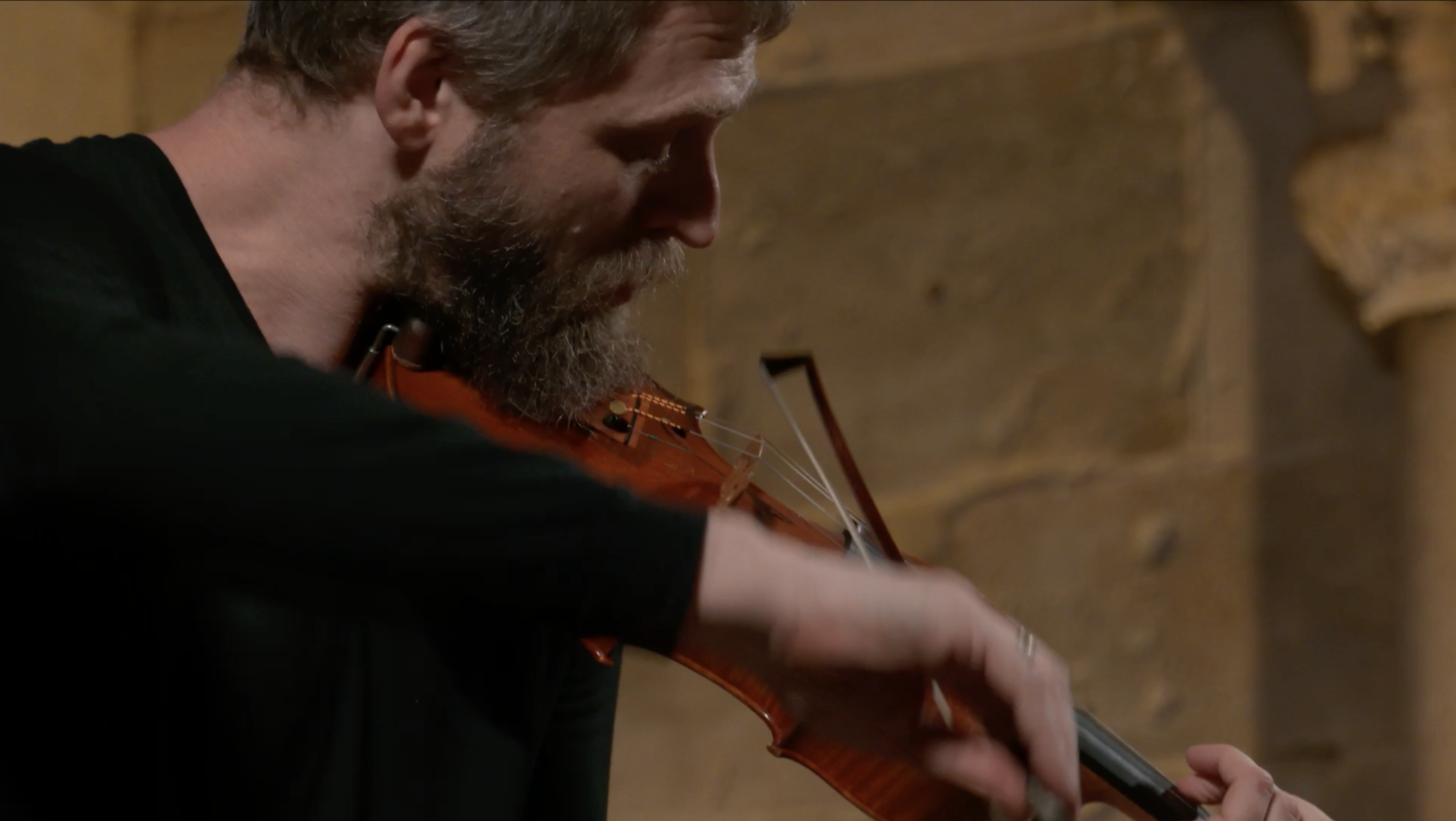 Man performing in all black, using the violin.