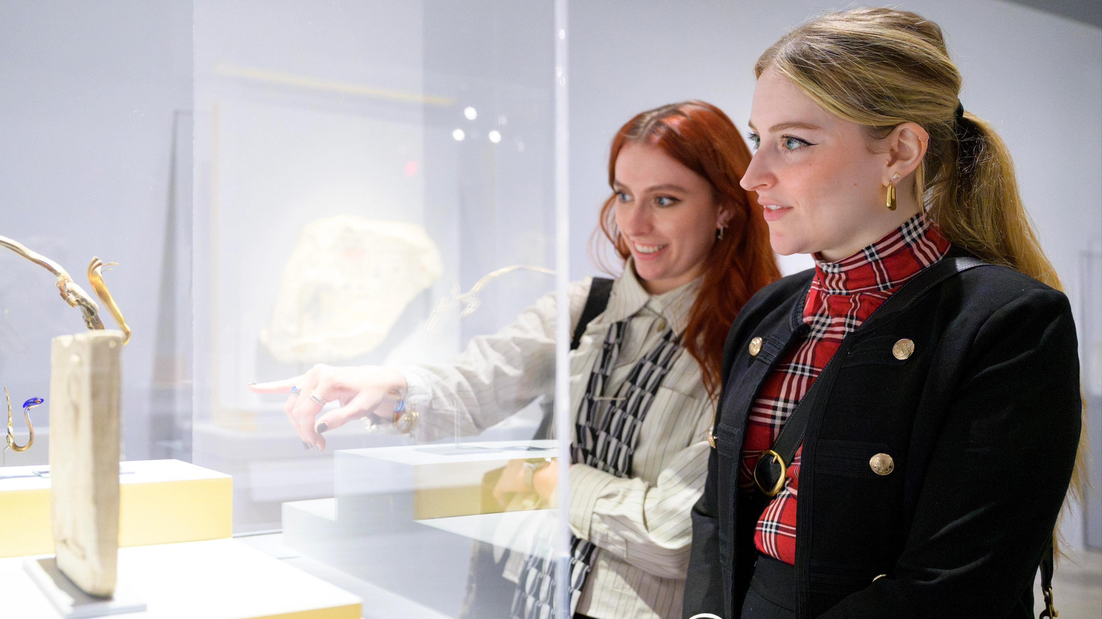 Two women pointing and looking at an artwork. 