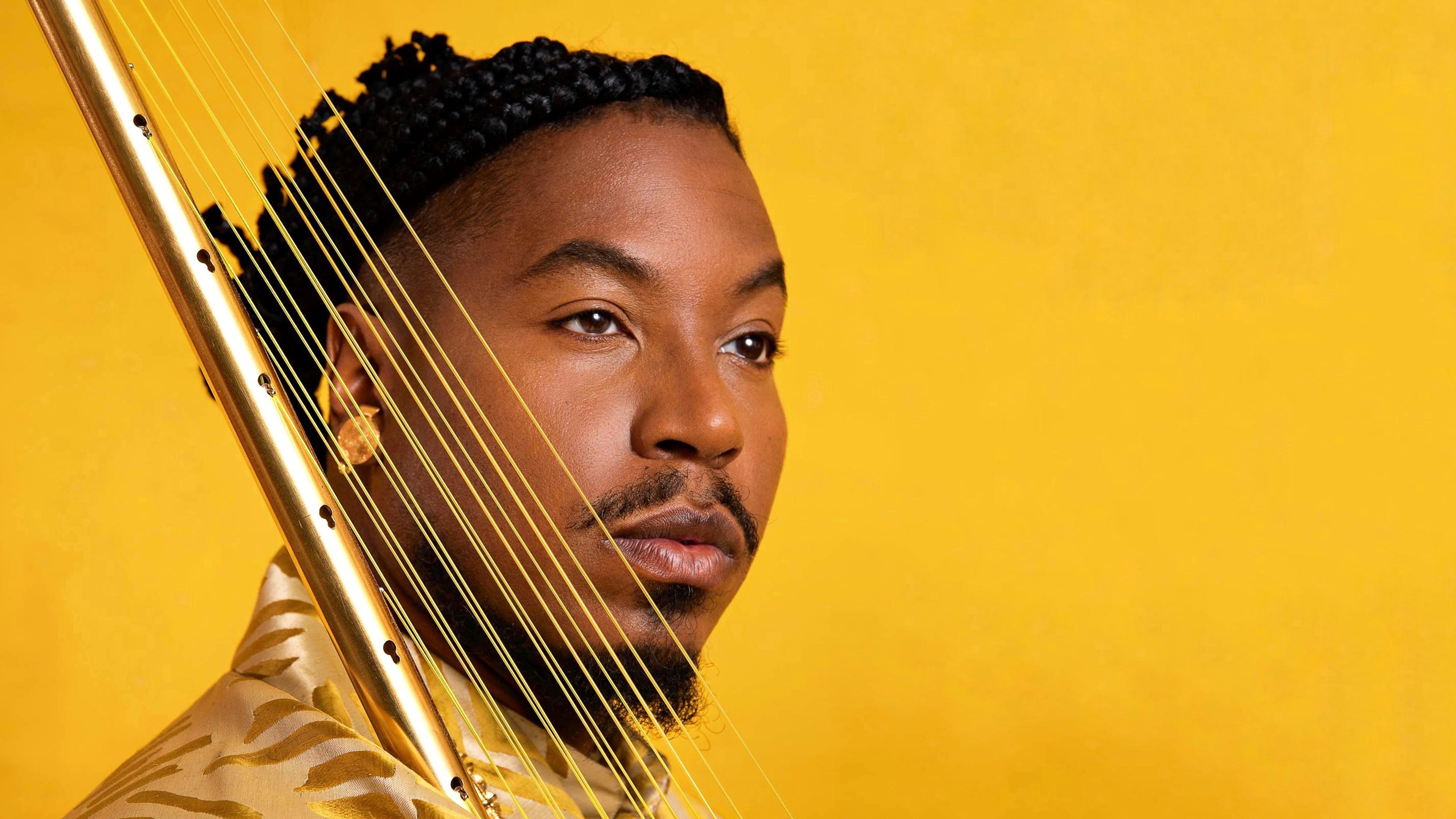 Photo of Chief Adjuah in front of a solid yellow background.