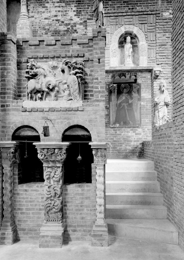 A brick stairwell with ornately carved pilasters, reliefs, and sculptures.