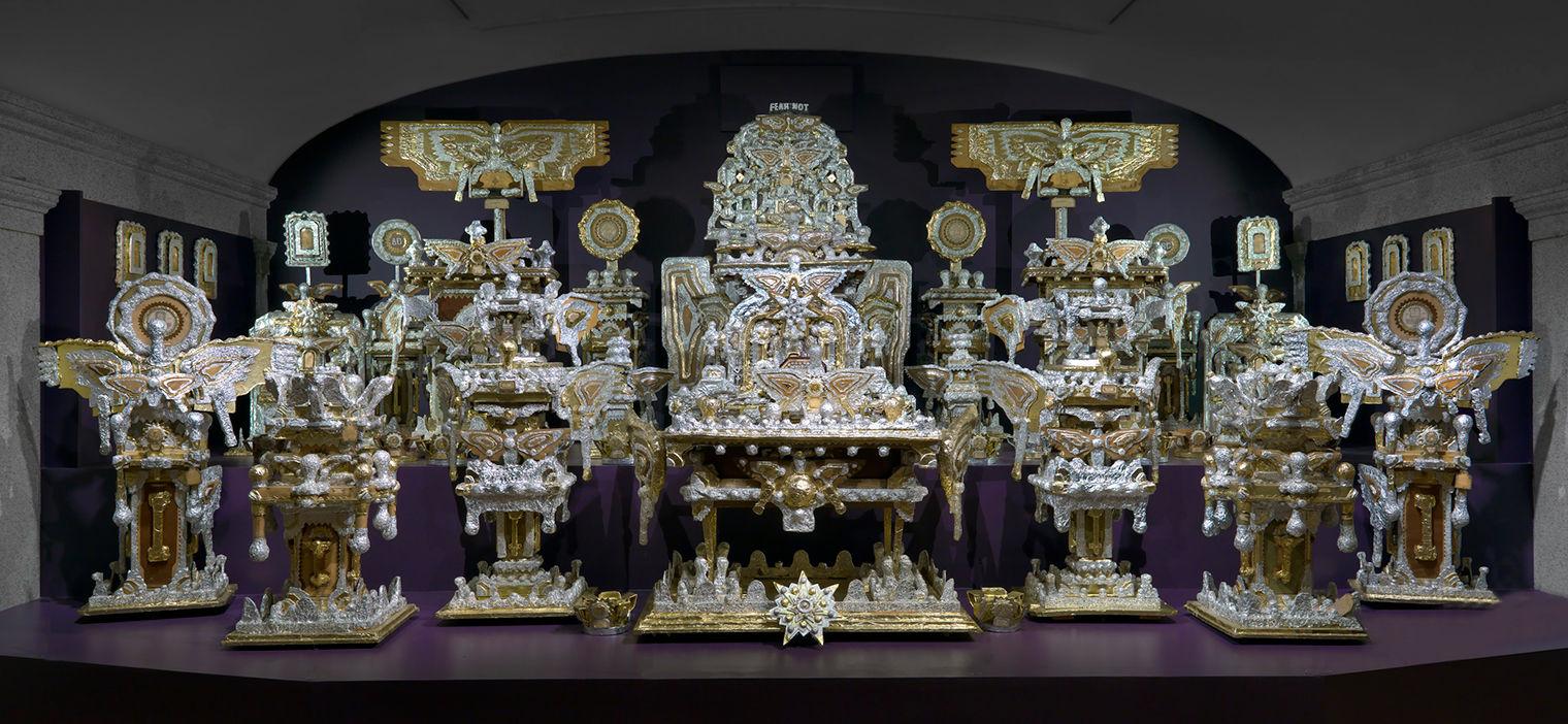 Elaborate artwork with a throne in the background, surrounded by religious-inspired objects. All of the objects shine in golds and silvers.