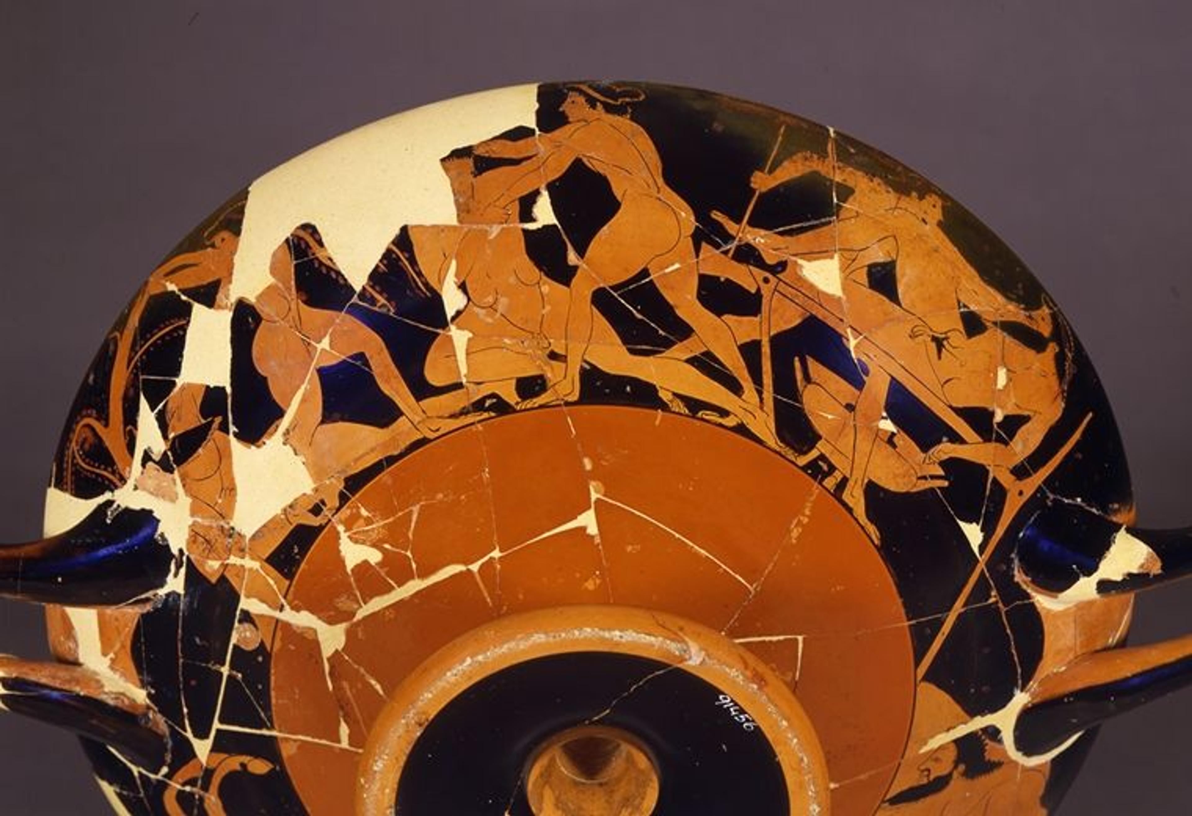 The bottom view of a red and black Greek drinking cup with illustrations of figures in action along the rim