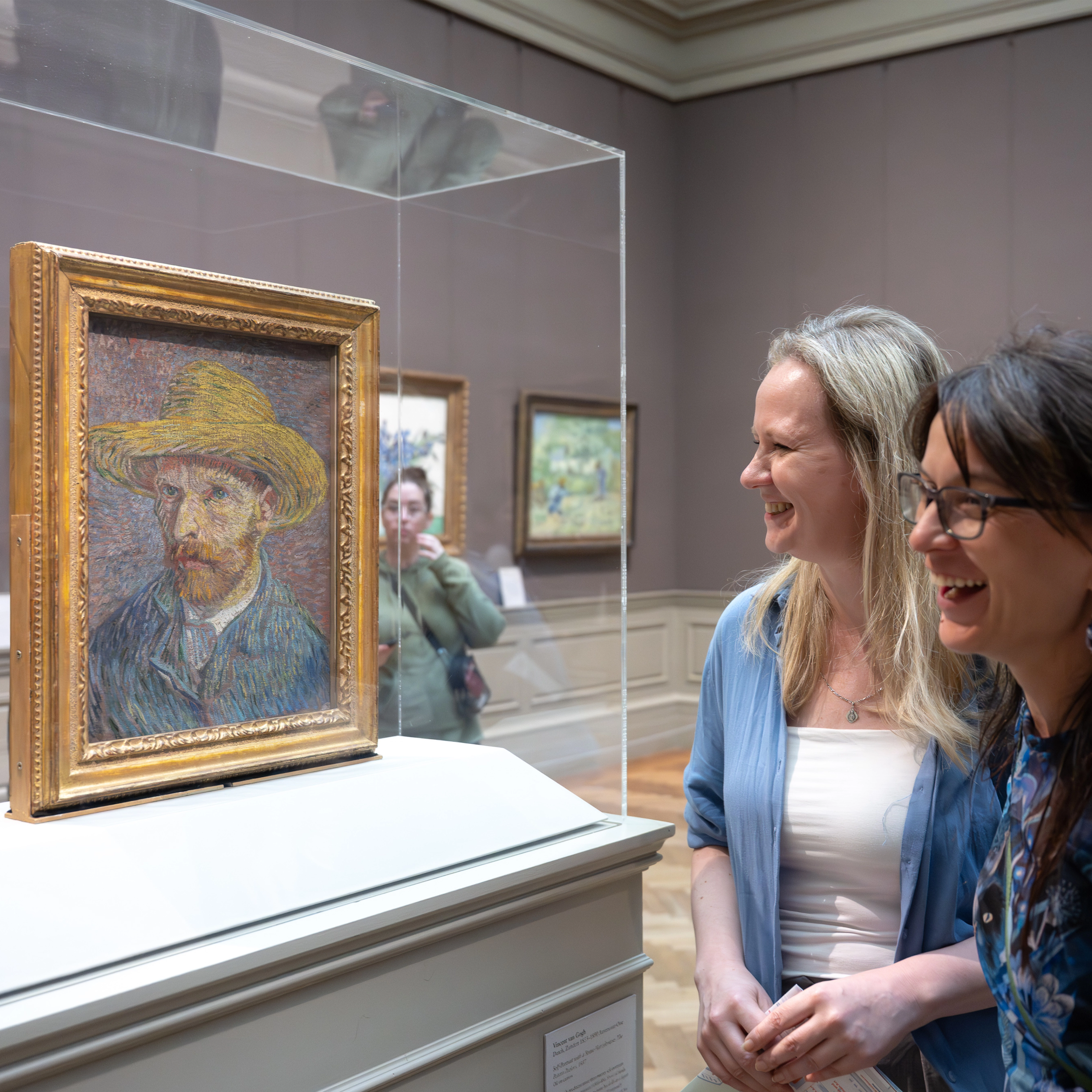 Two women in front of Self-Portrait with a Straw Hat (obverse: The Potato Peeler)