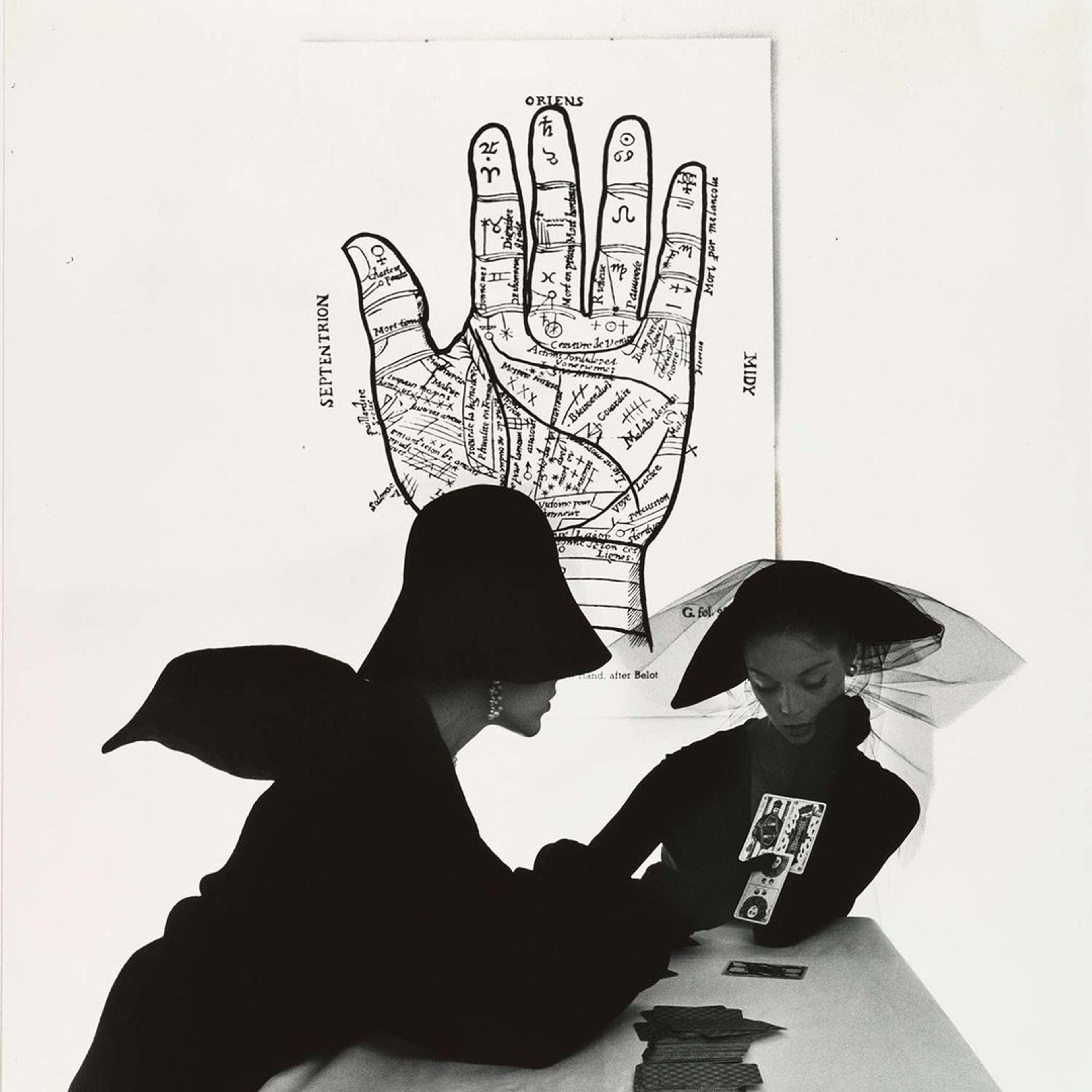 Irving Penn's "The Tarot Reader (Bridget Tichenor and Jean Patchett), New York" with two women in stylist black clothing reading tarot cards with a diagram of a hand behind them