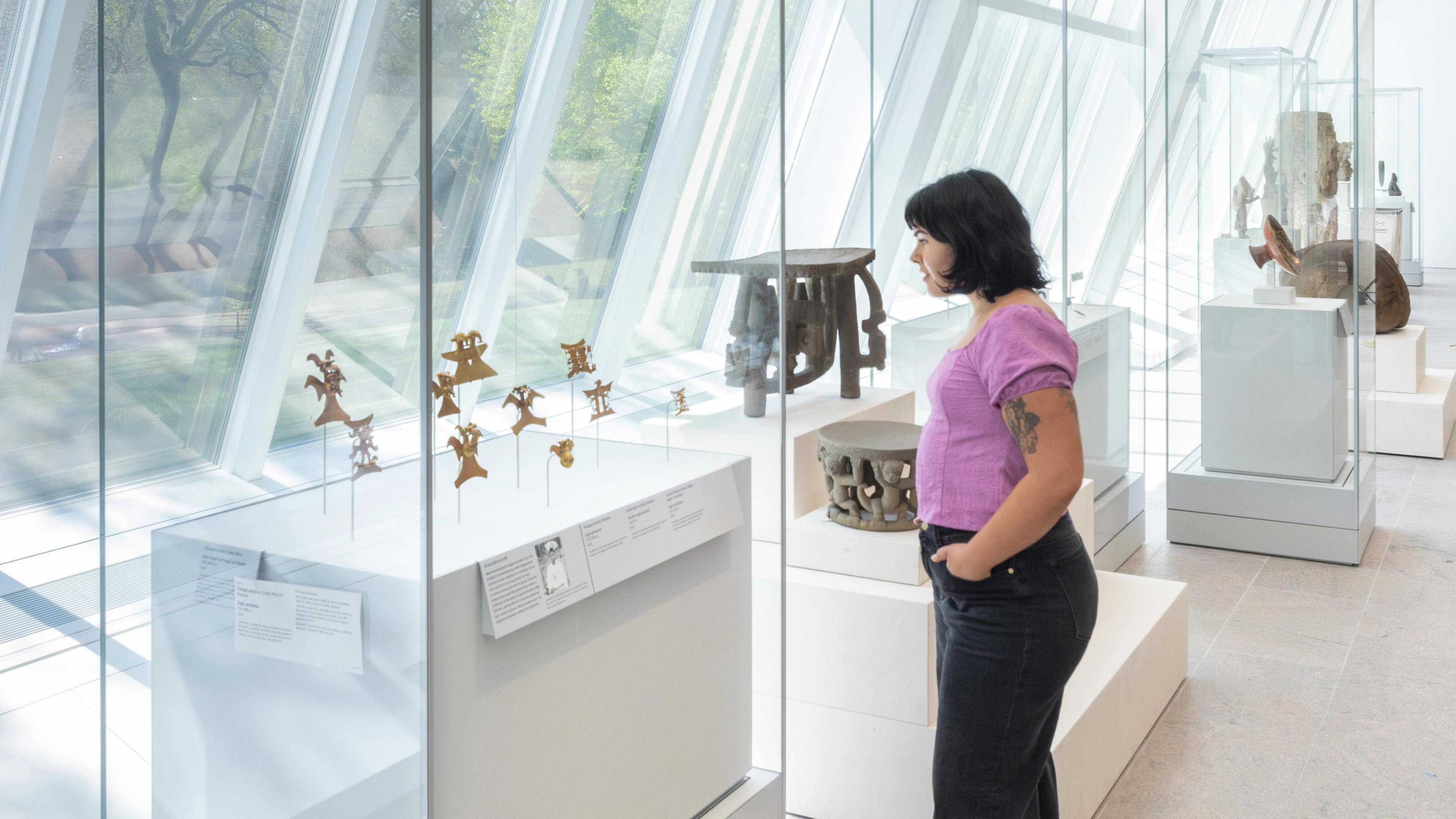 Woman looking closely at gold objects in Gallery 360, Arts of the Ancient Americas, The Michael C. Rockefeller Wing.