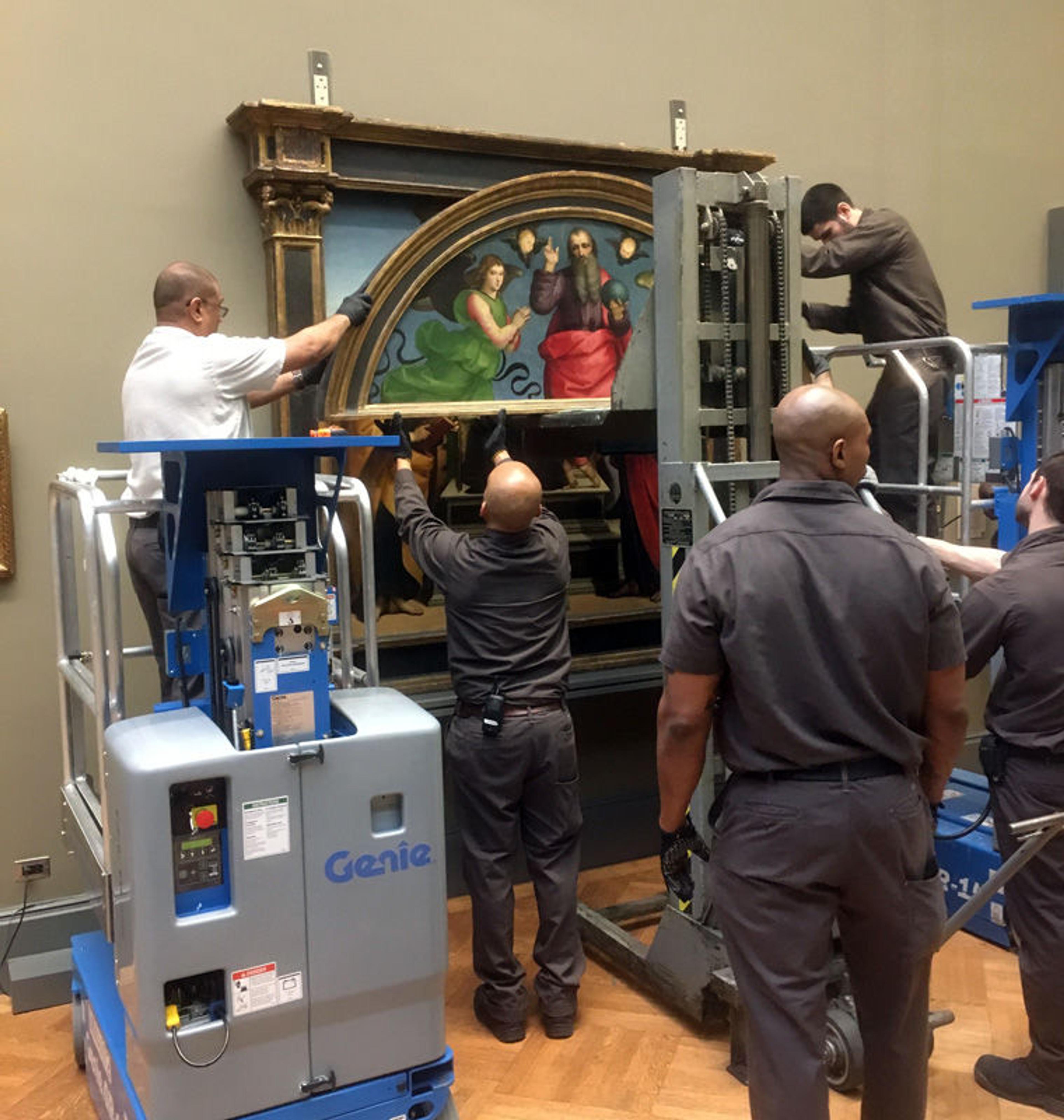 Museum staff remove the lunette (top part) from an altarpiece by Raphael in an art gallery