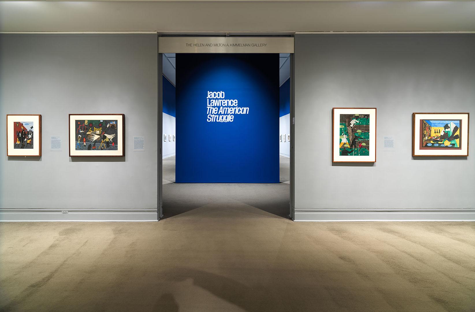 A photograph of four paintings hanging on either side of a blue door