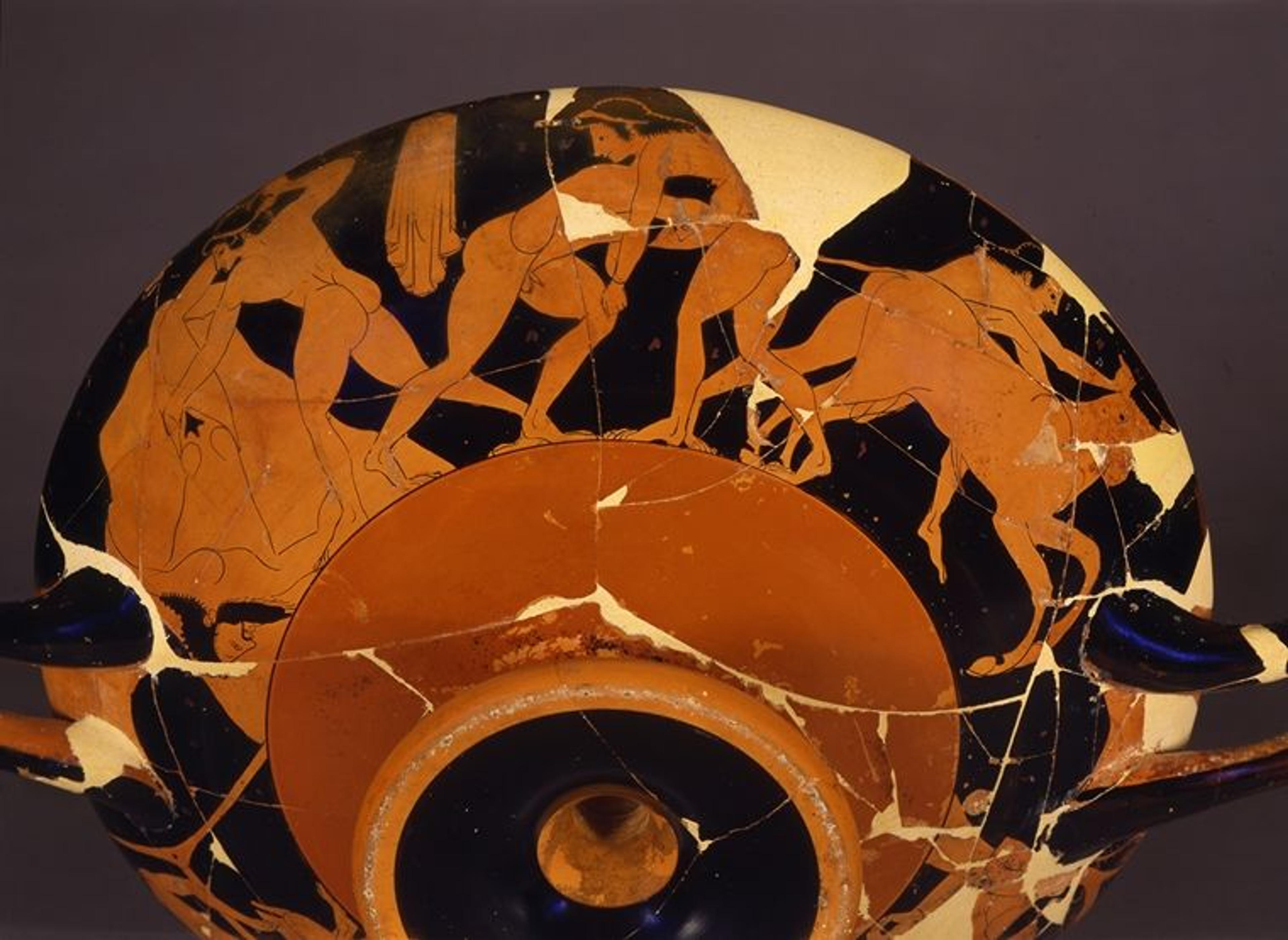 The bottom view of a red and black Greek drinking cup with illustrations of figures in action along the rim