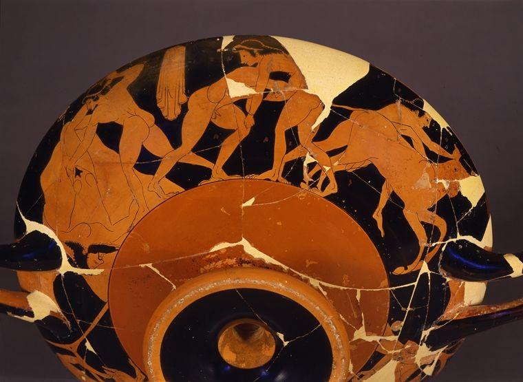 The bottom view of a red and black Greek drinking cup with illustrations of figures in action along the rim