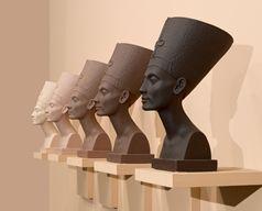 Five sculptures of busts of a woman in gradient shades of brown on a shelf