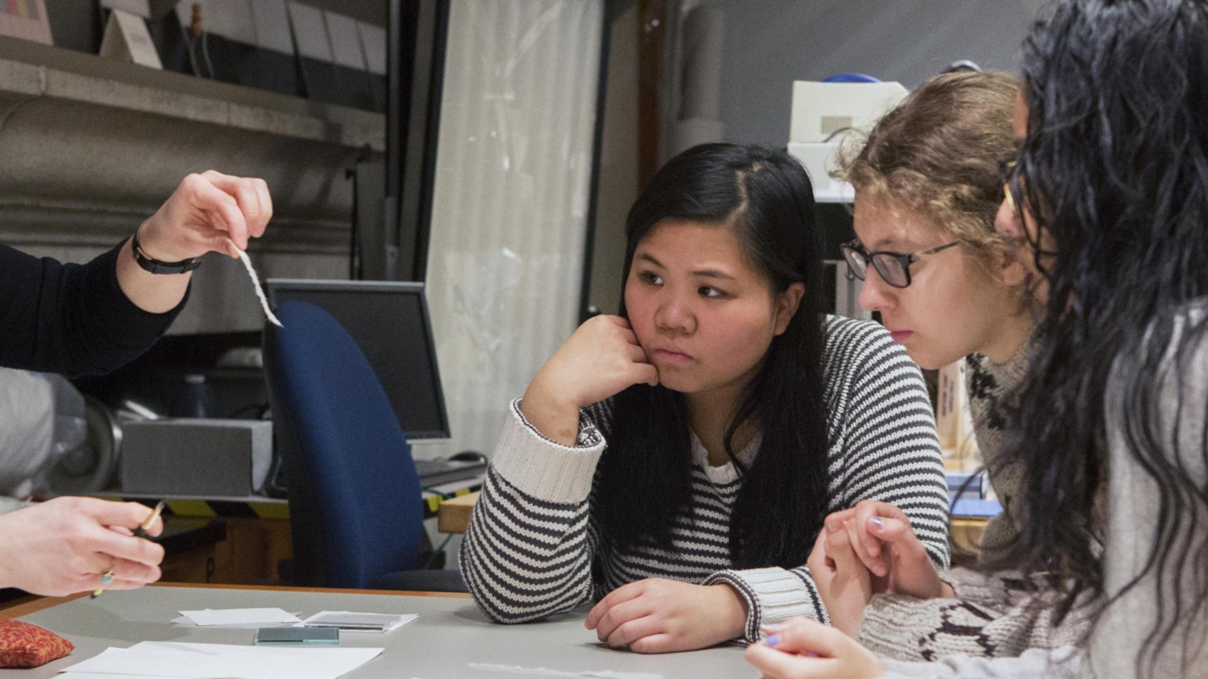 A group of students study an object.