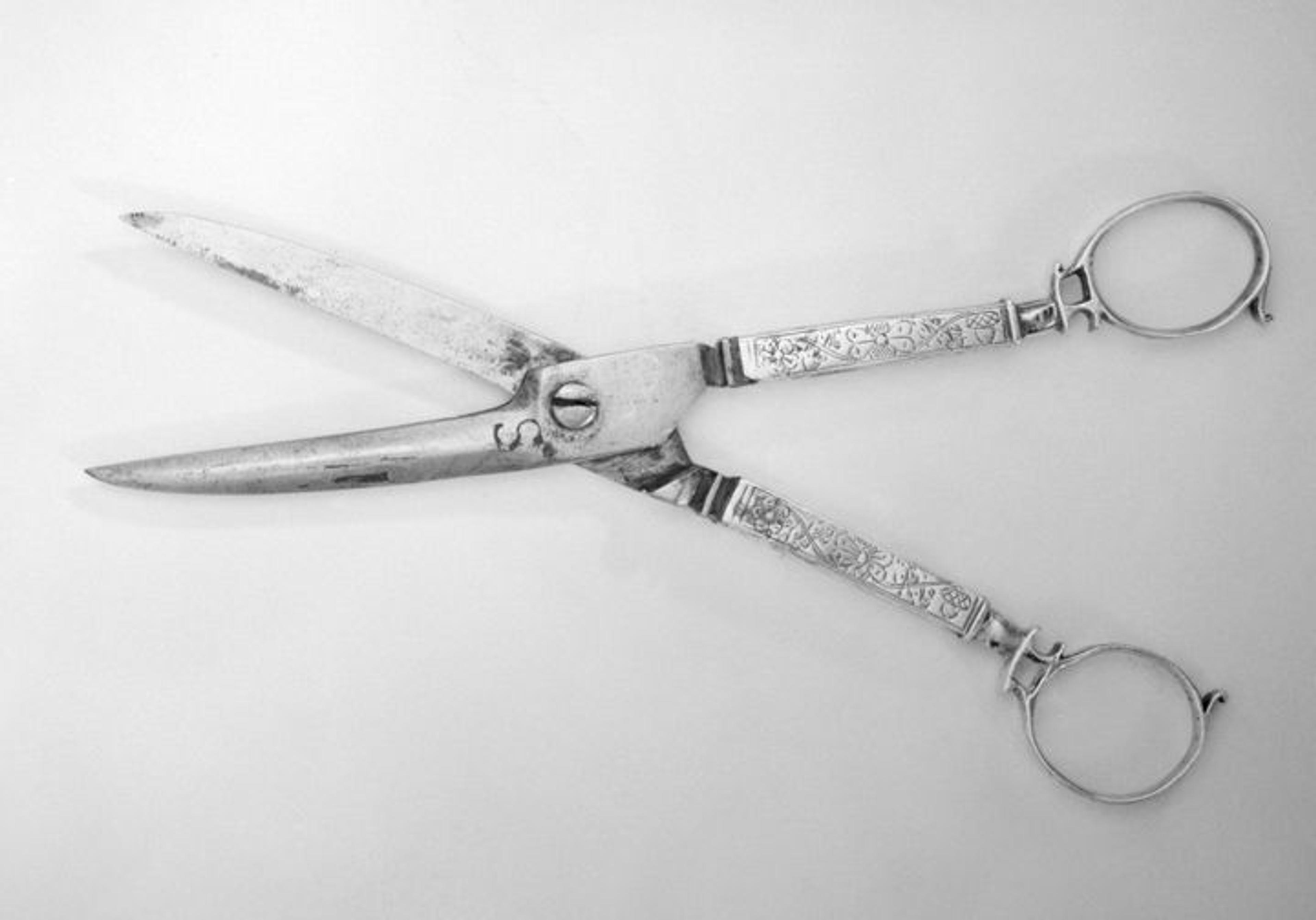 A silver set of sewing scissors featuring long handles engraved with flowers