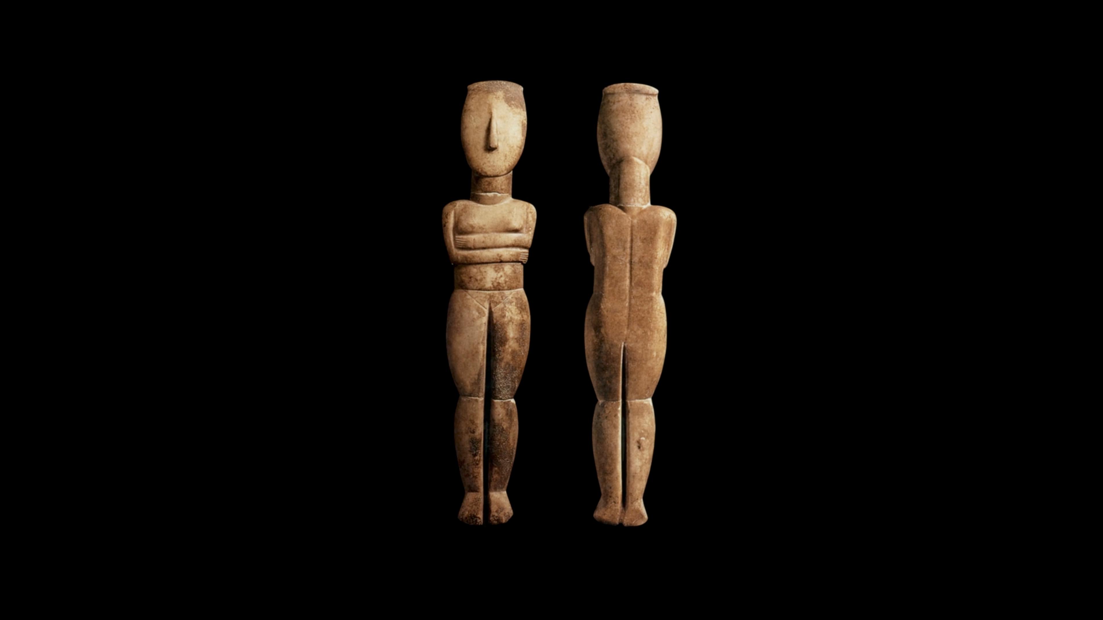 Two cycladic figures—one facing the viewer and one with its back to the viewer—against a black background