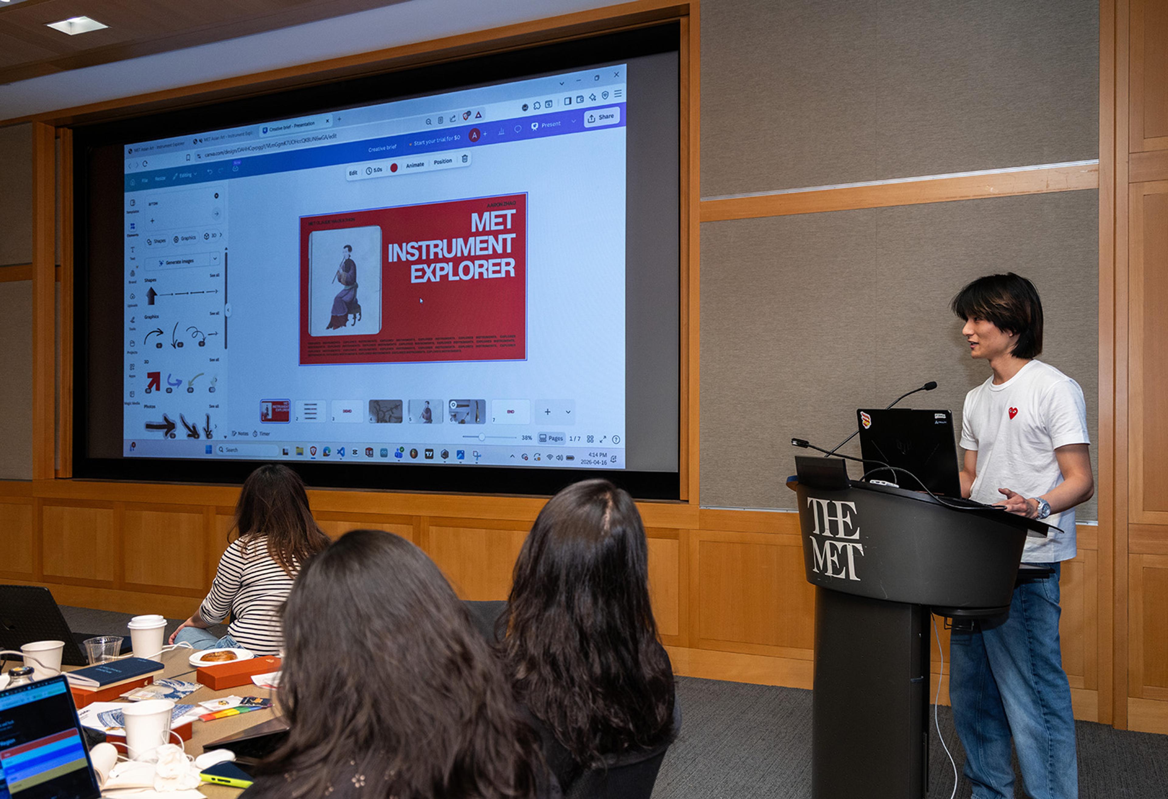 Young man presents at The Met podium with a large slide showing "MET Instrument Explorer" on screen.