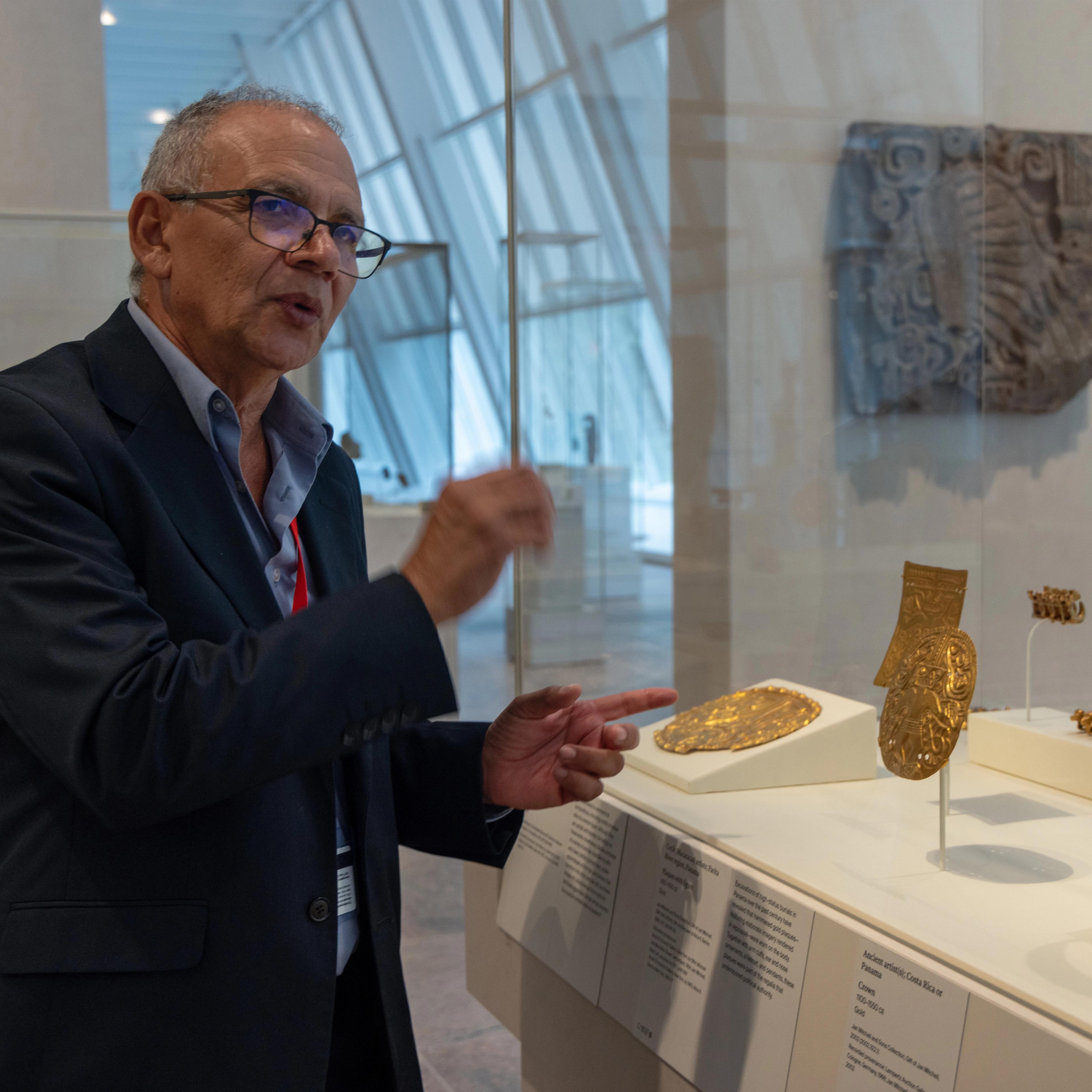 Francisco Corrales Ulloa talking in front of a gold plaque in the Arts of the Ancient Americas galleries